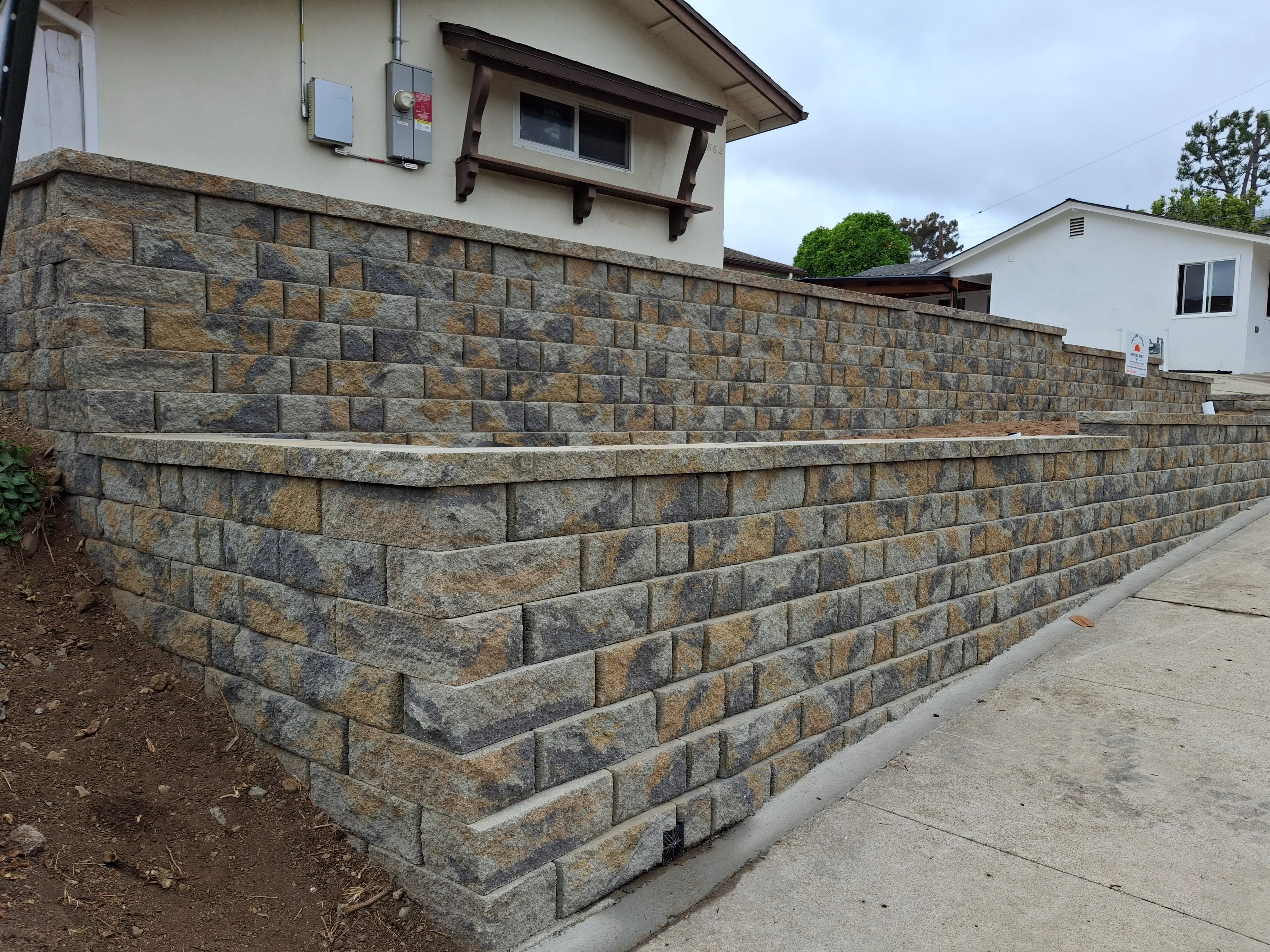 Segmental retaining wall with textured concrete blocks and cap stone
