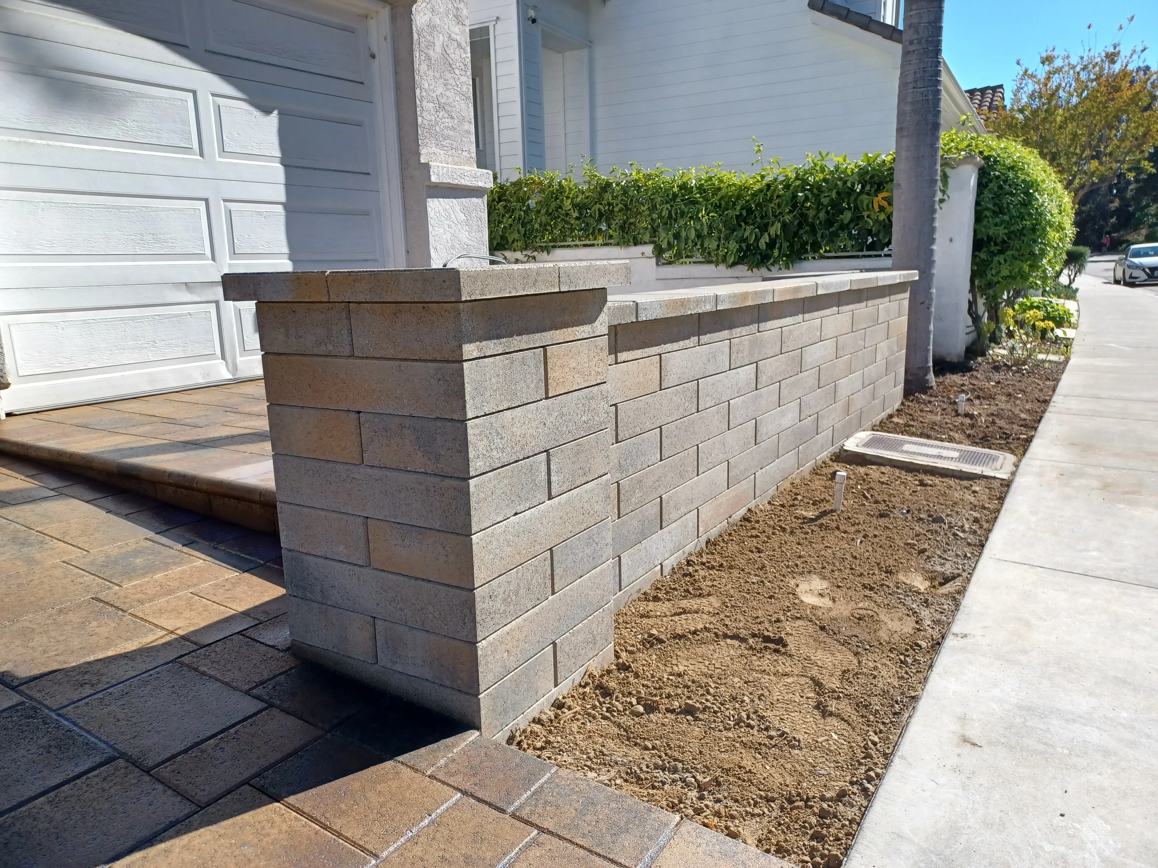 Stacked concrete block retaining wall with coping cap and corner pillar detail
