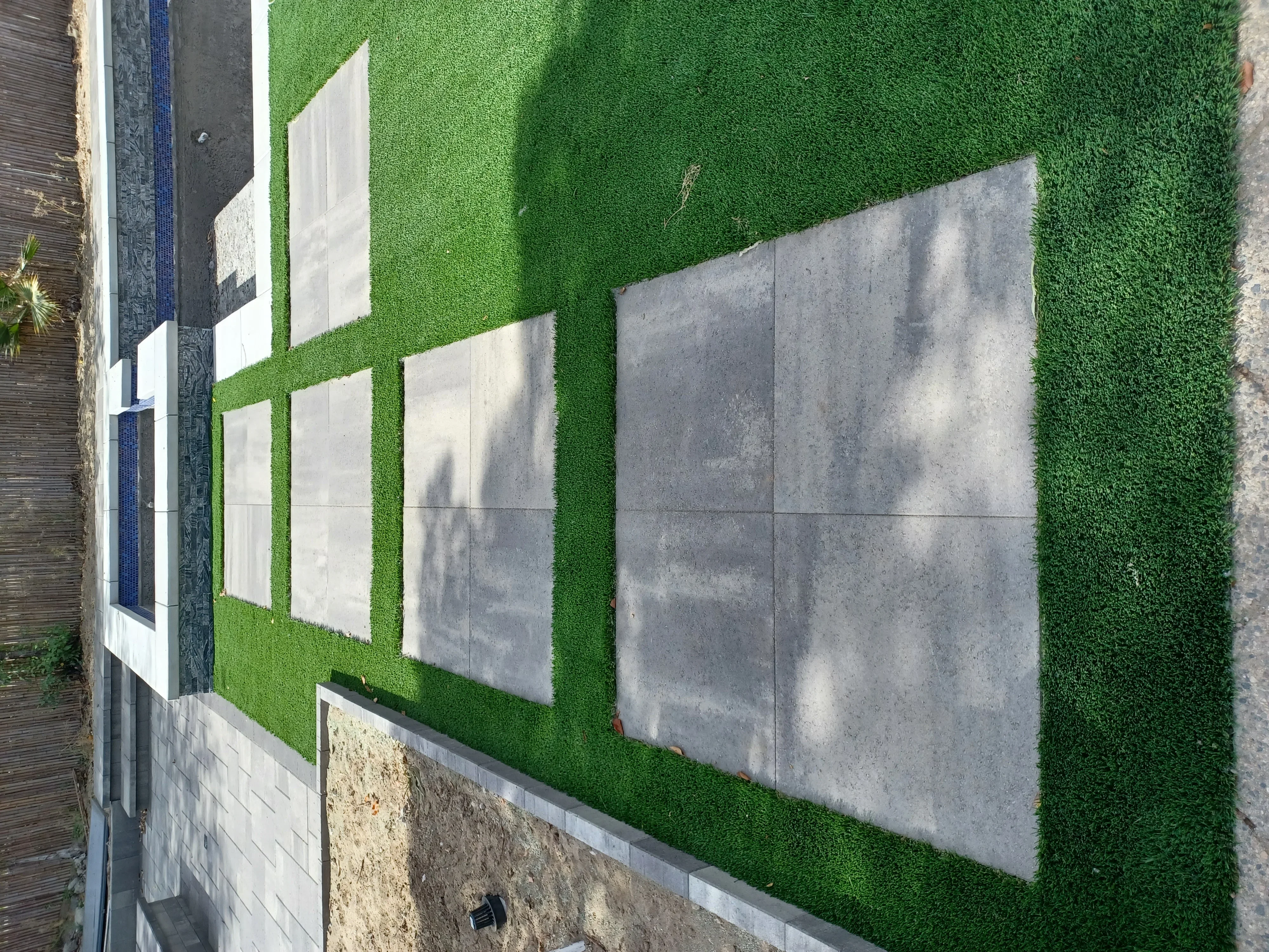Artificial turf with concrete pavers and white trim edging along building foundation
