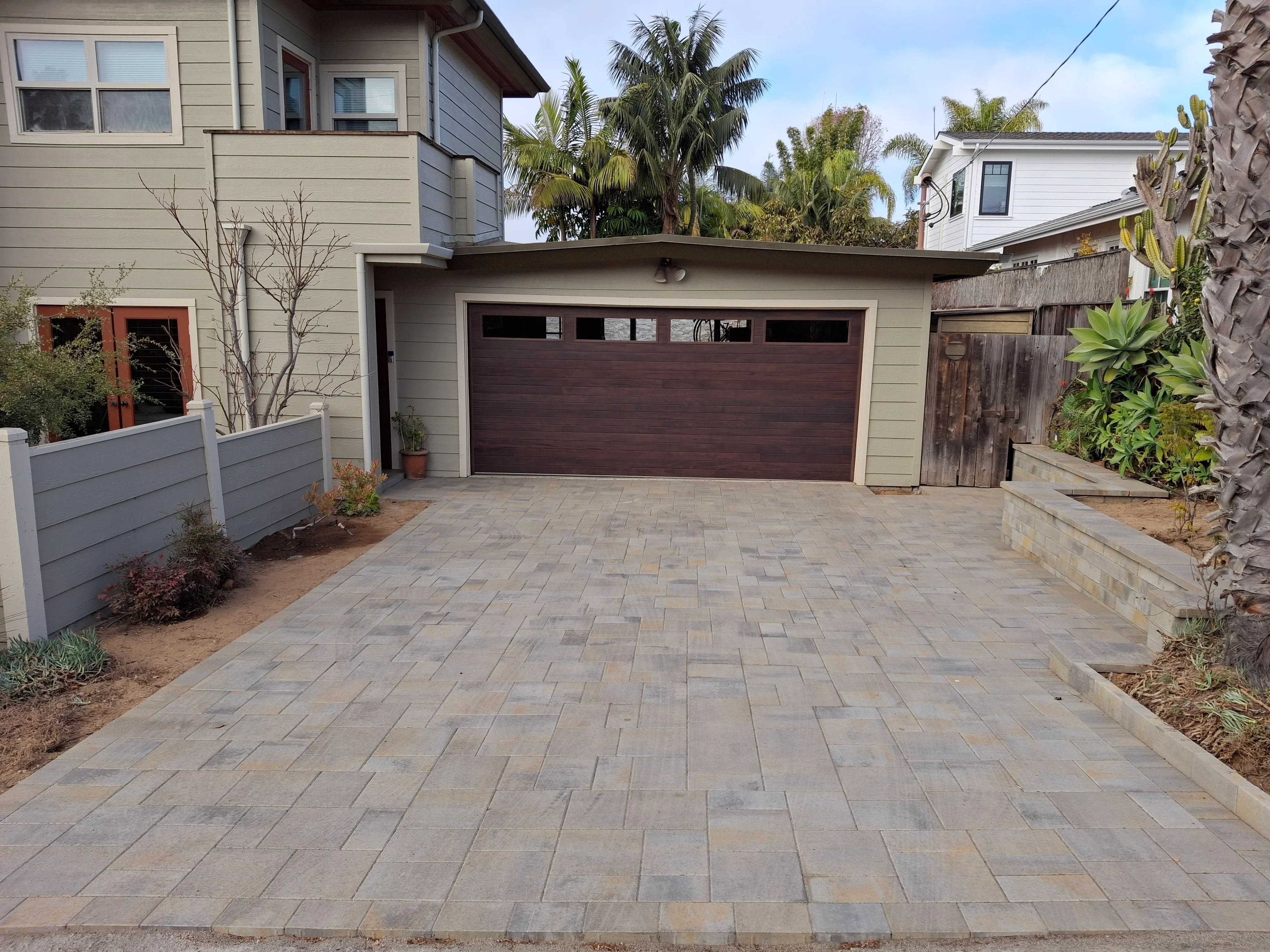 Herringbone pattern permeable paver driveway with concrete curbing and new landscaping borders