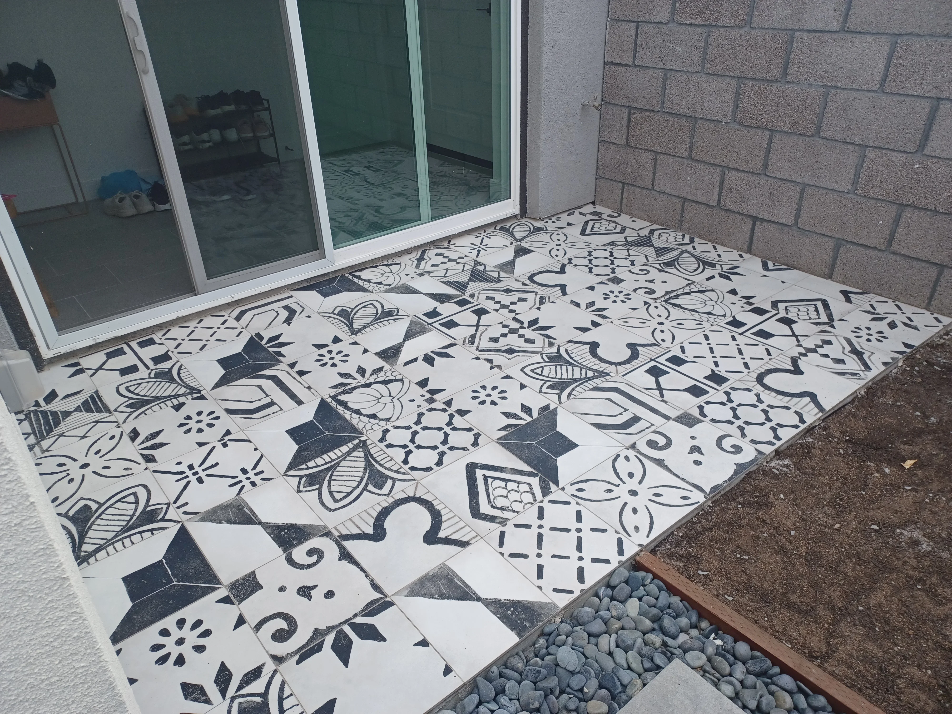 Black and white patterned ceramic tile patio with geometric and floral designs installed next to home