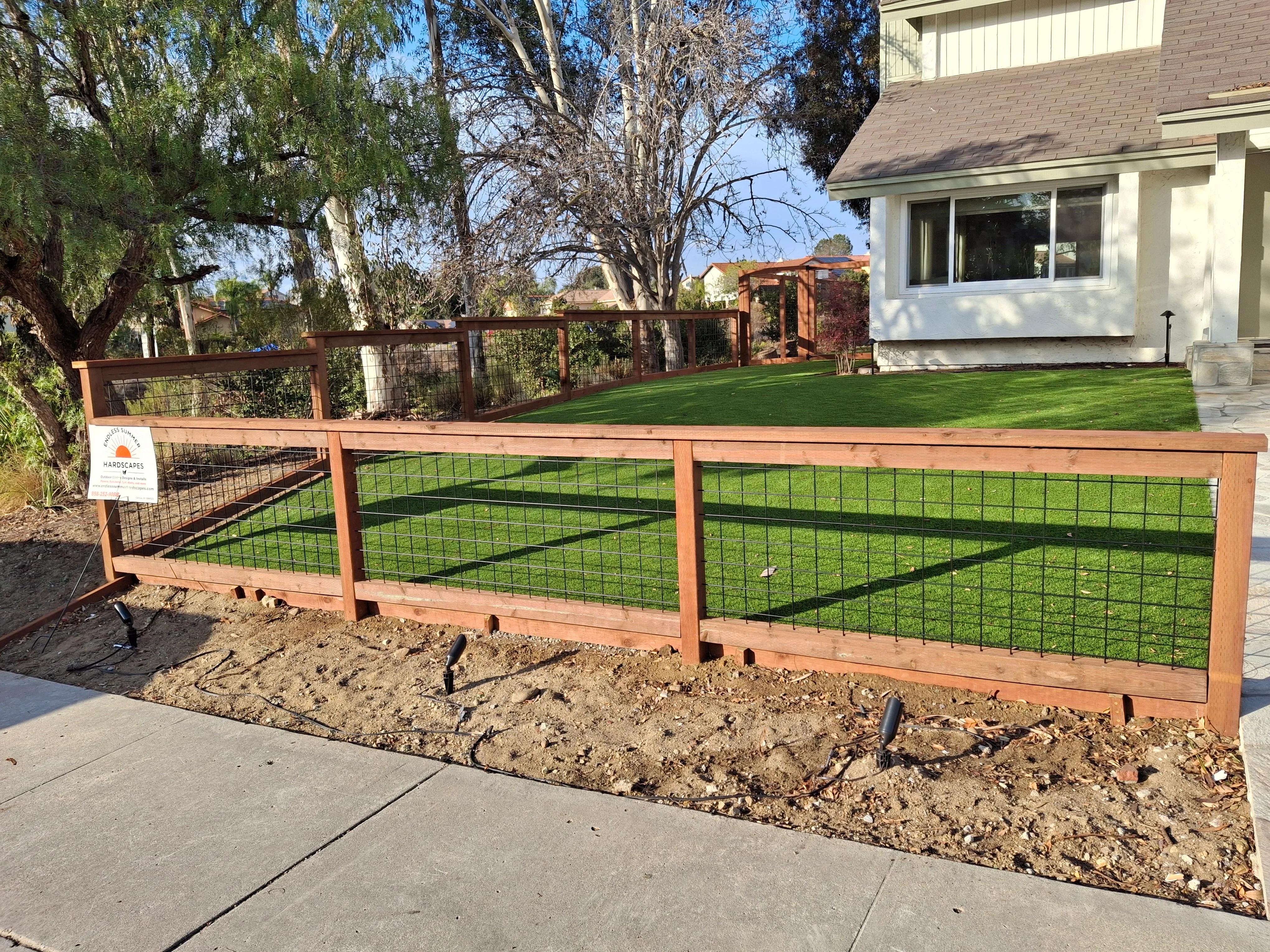 Wood post and metal mesh driveway fence with concrete footings and stained timber framing