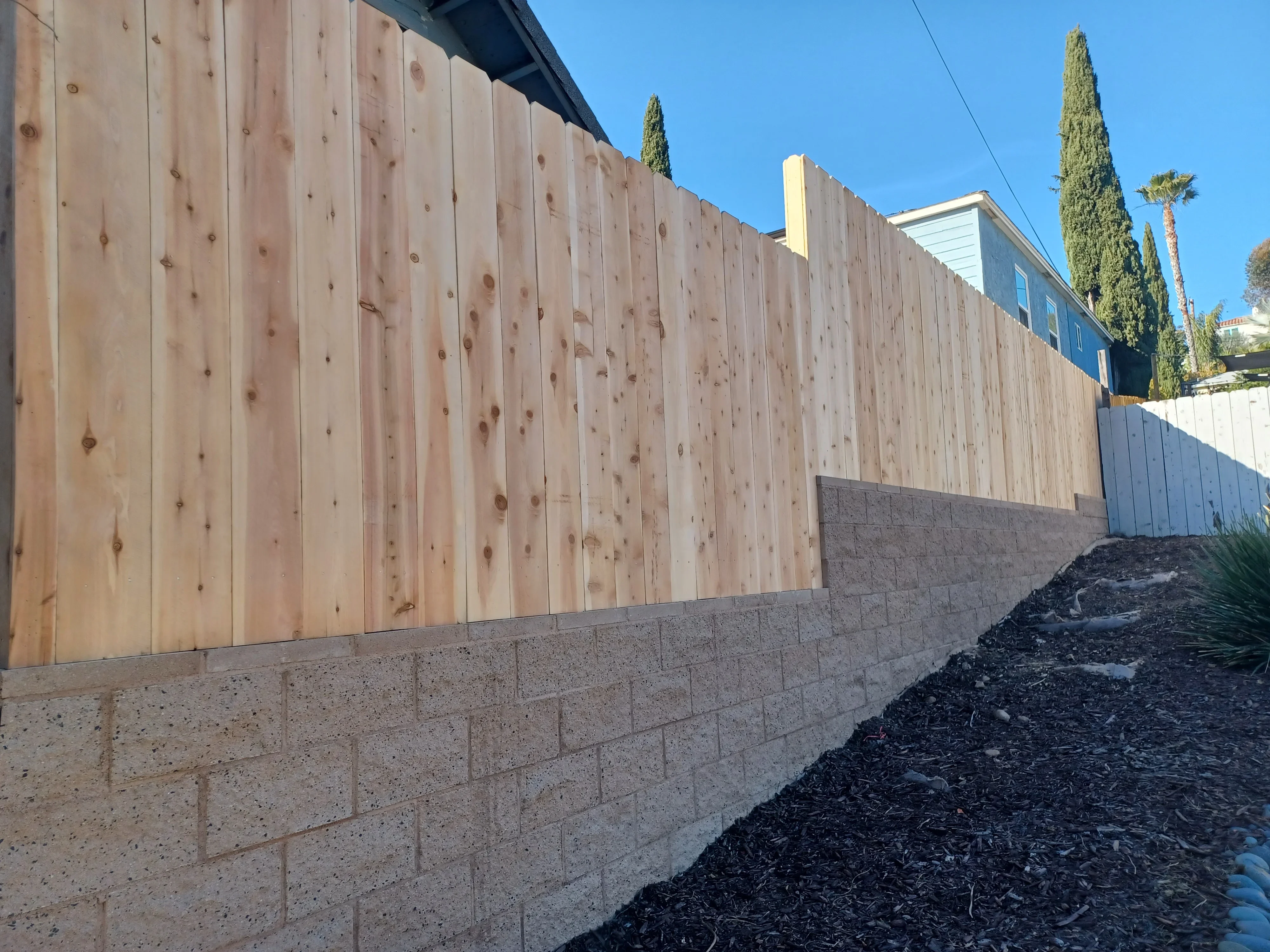 Concrete block retaining wall with horizontal cedar wood fence panels installed on residential property