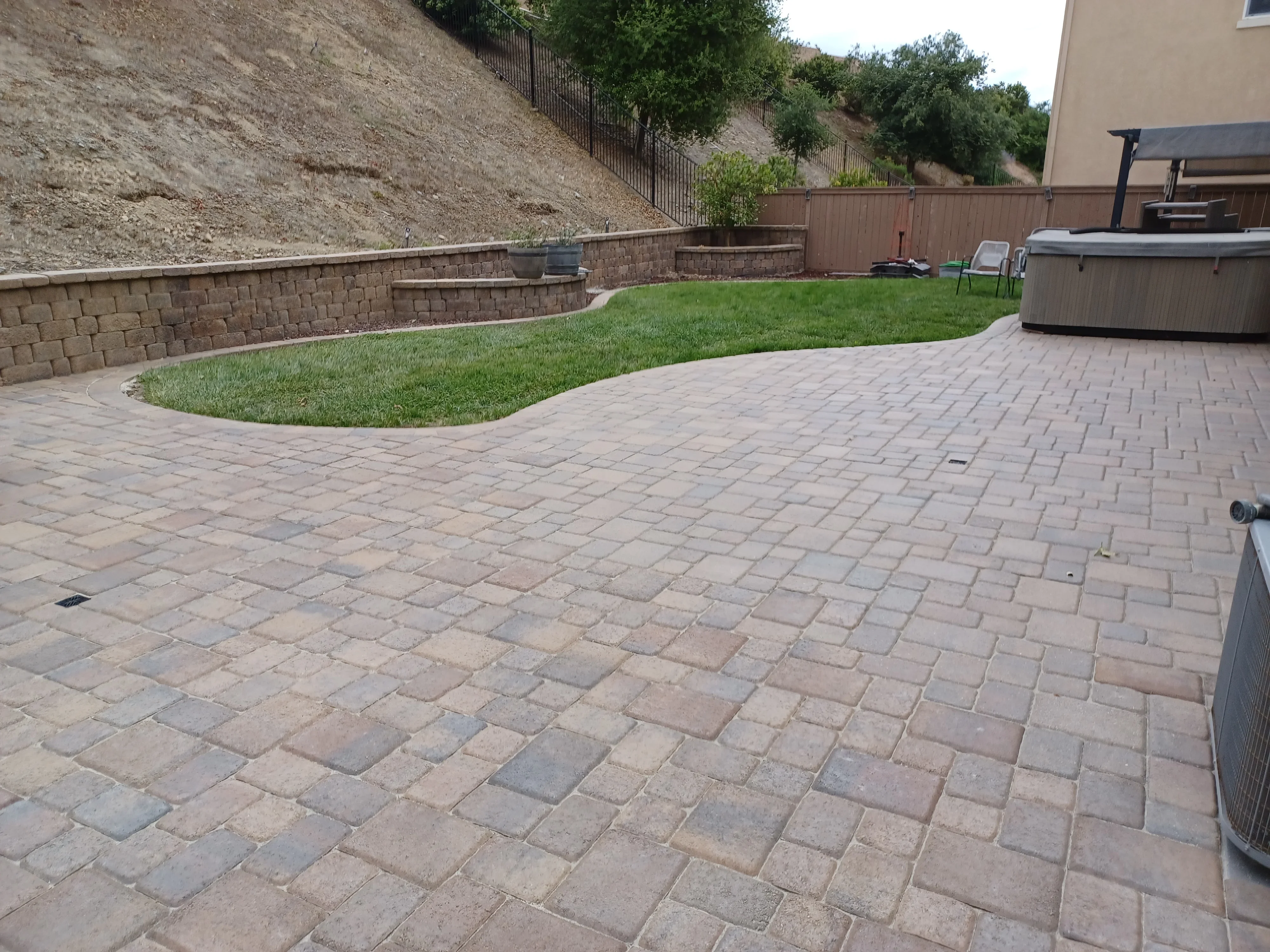Permeable paver patio with running bond pattern and tiered segmental retaining wall on sloped terrain