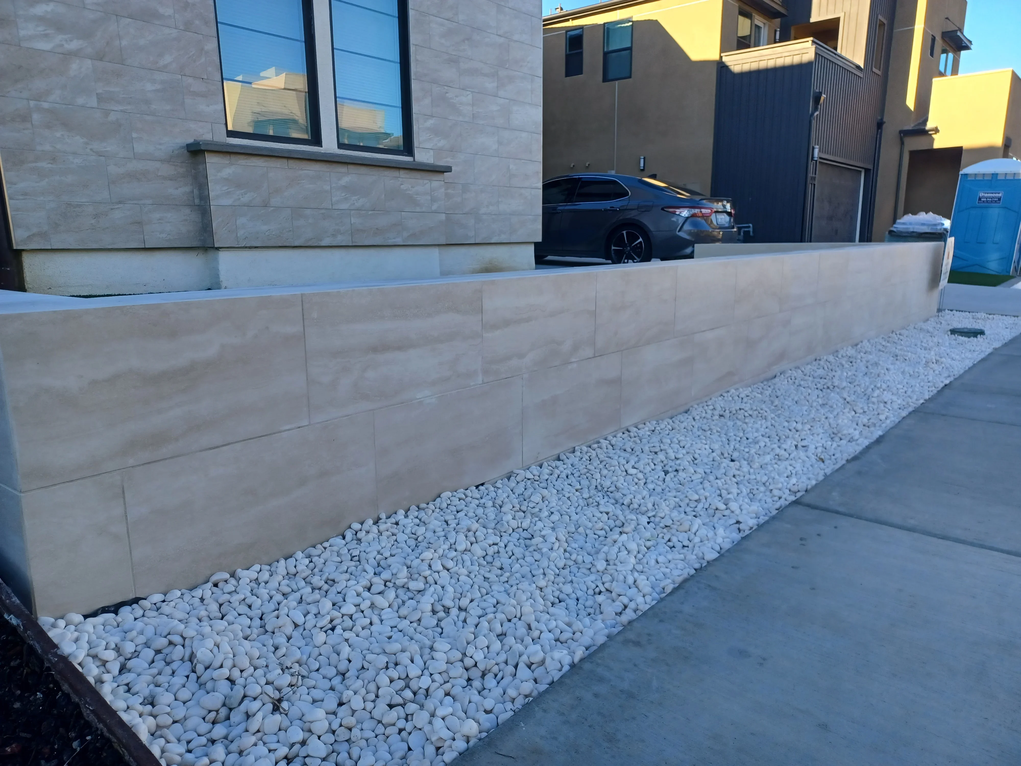 Stacked stone retaining wall with white river rock base and concrete construction