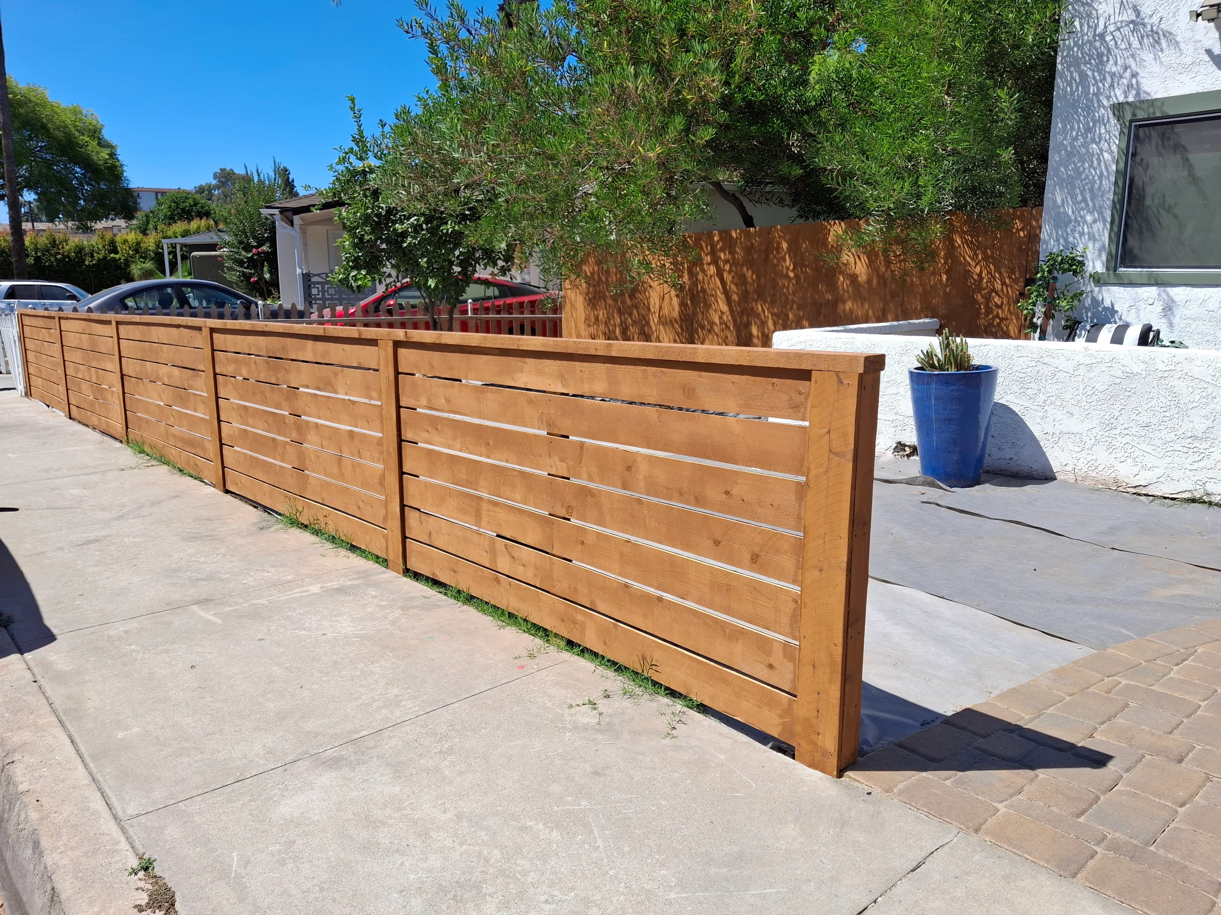 Horizontal cedar wood fence with metal supports along residential driveway