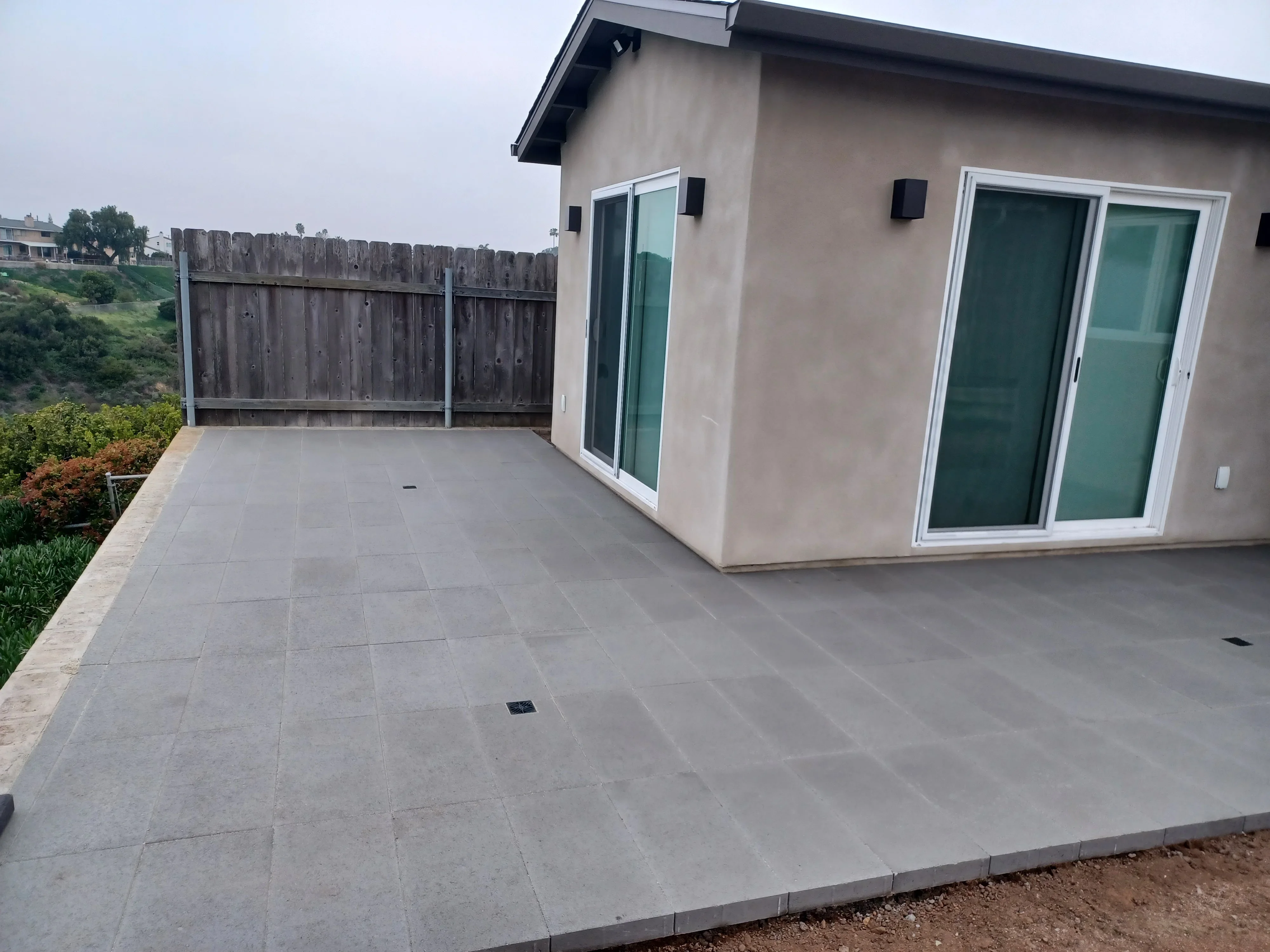 Gray concrete paver patio and driveway with uniform grout lines and drainage features