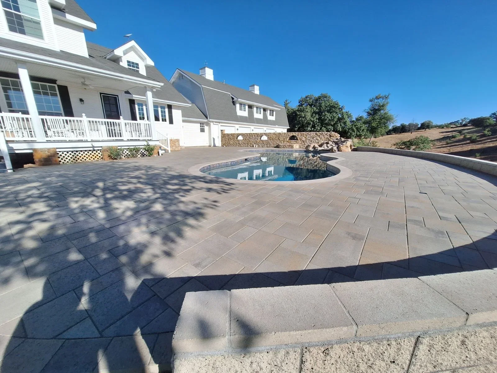 Permeable paver patio with herringbone pattern surrounding spa, stone water feature, and border detail