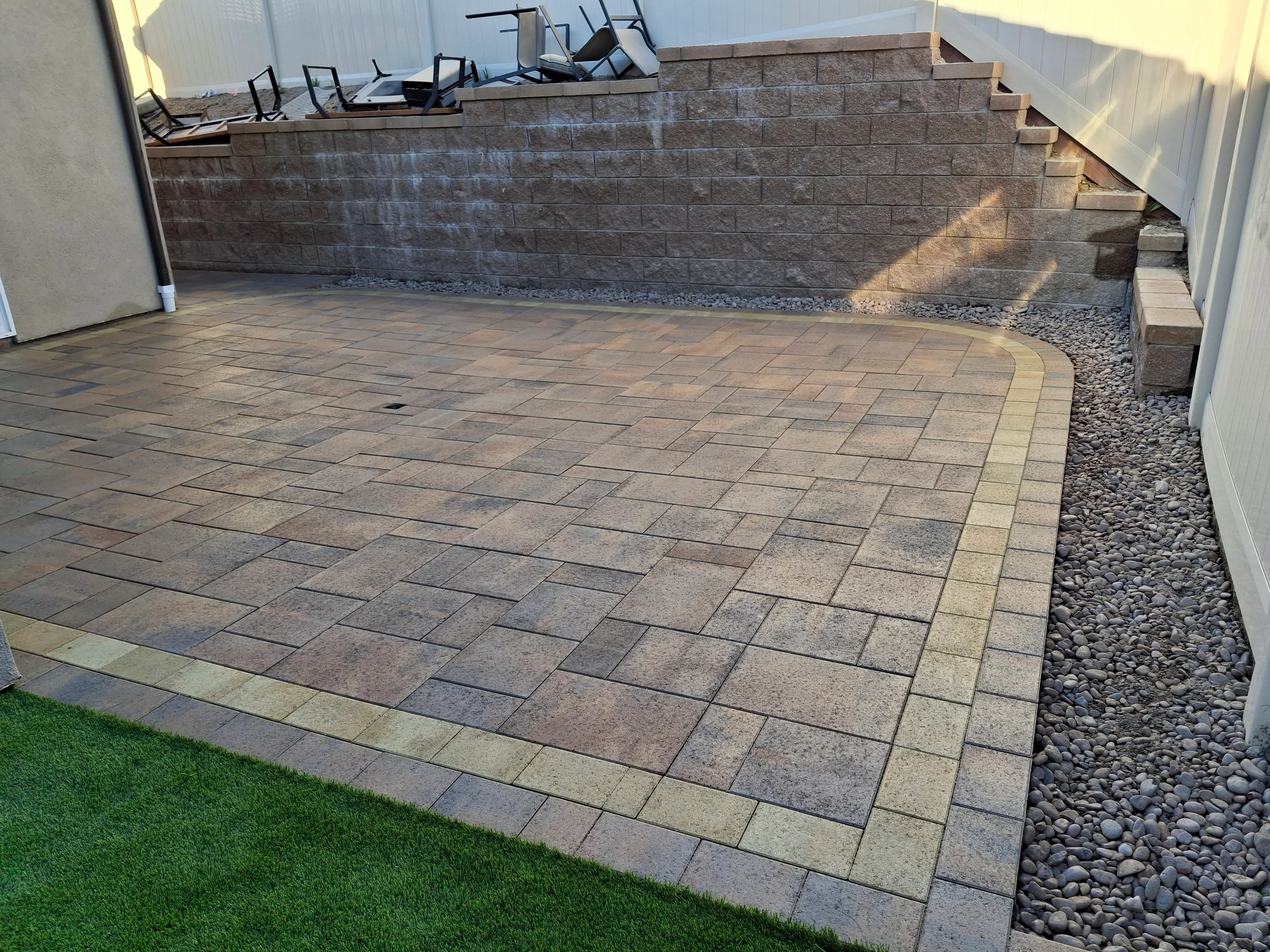 Concrete paver patio with running bond pattern and stone retaining wall installation