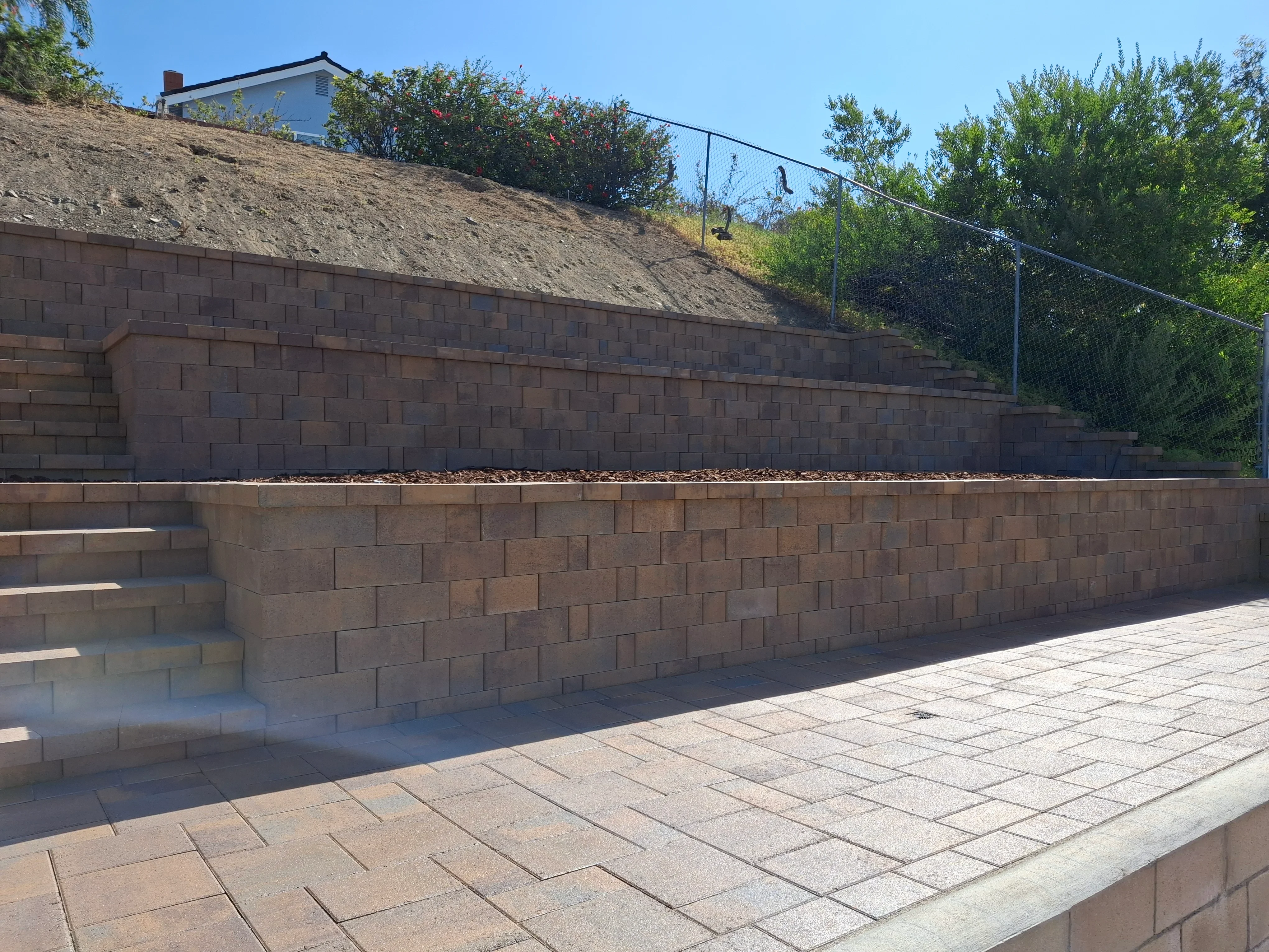 Tiered concrete block retaining wall with paver patio and integrated steps