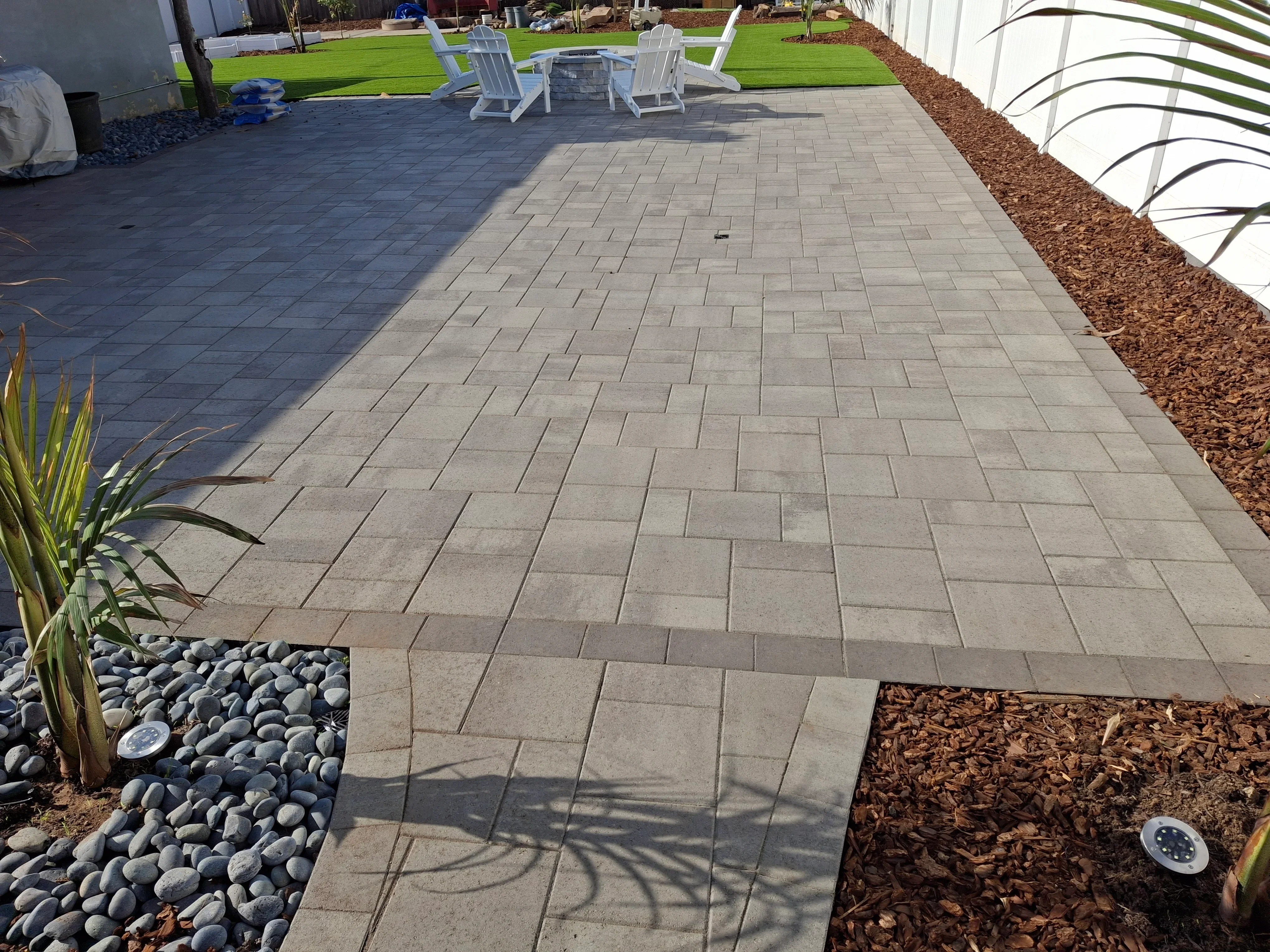 Concrete permeable pavers in running bond pattern with river rock and mulch borders