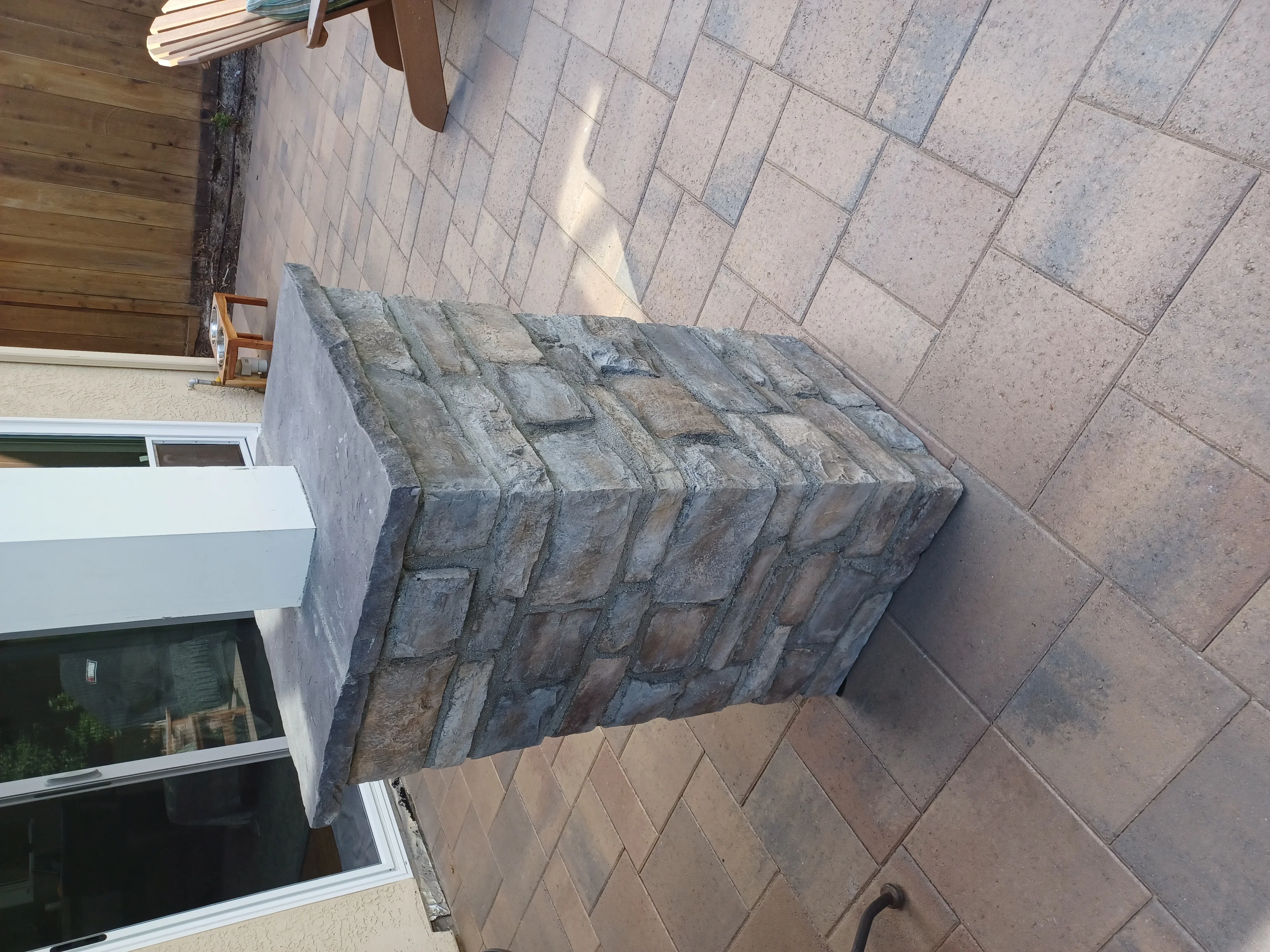 Stacked stone planter wall with gray textured blocks on paver patio