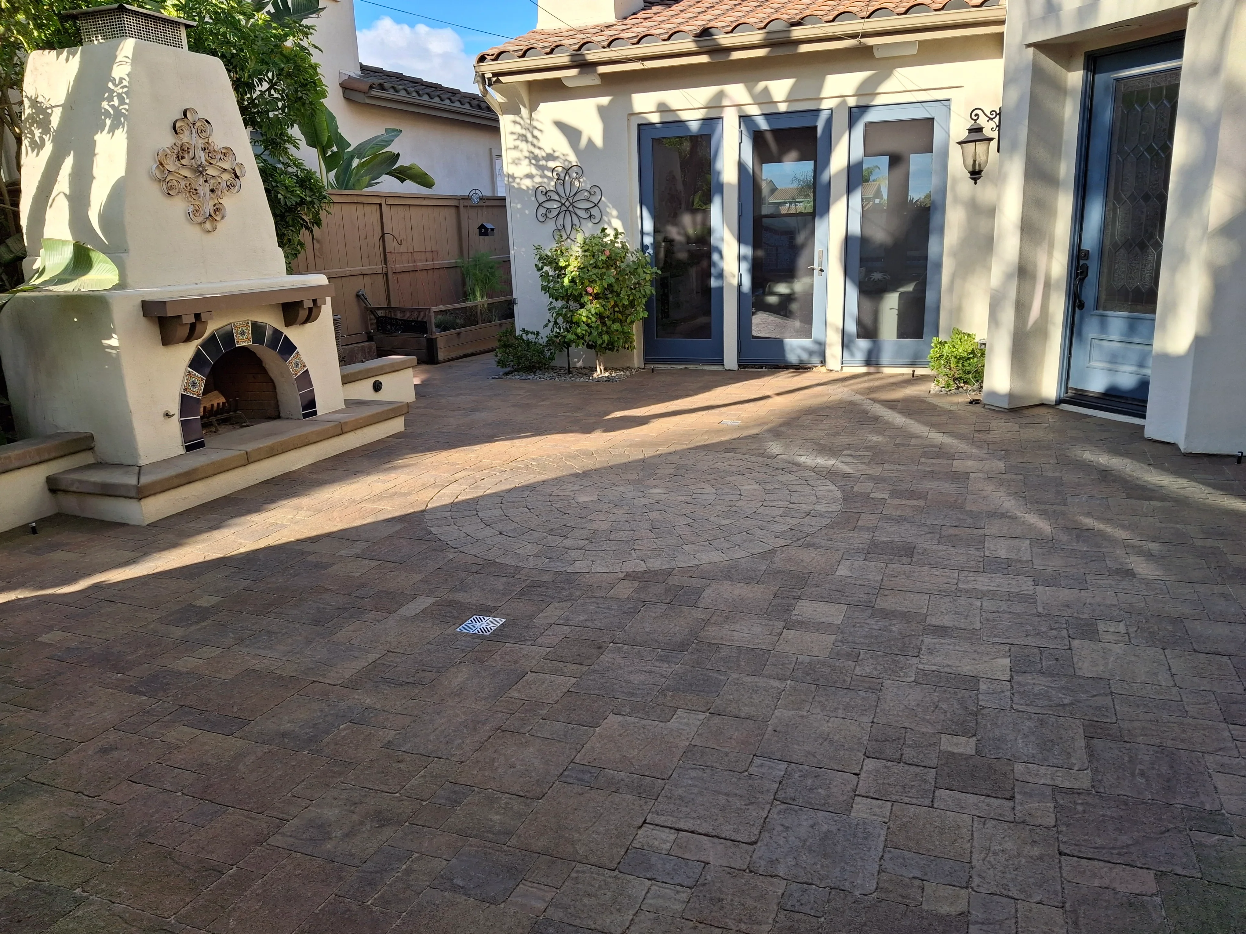 Herringbone paver courtyard with circular inlay pattern, charcoal and tan pavers, drainage system