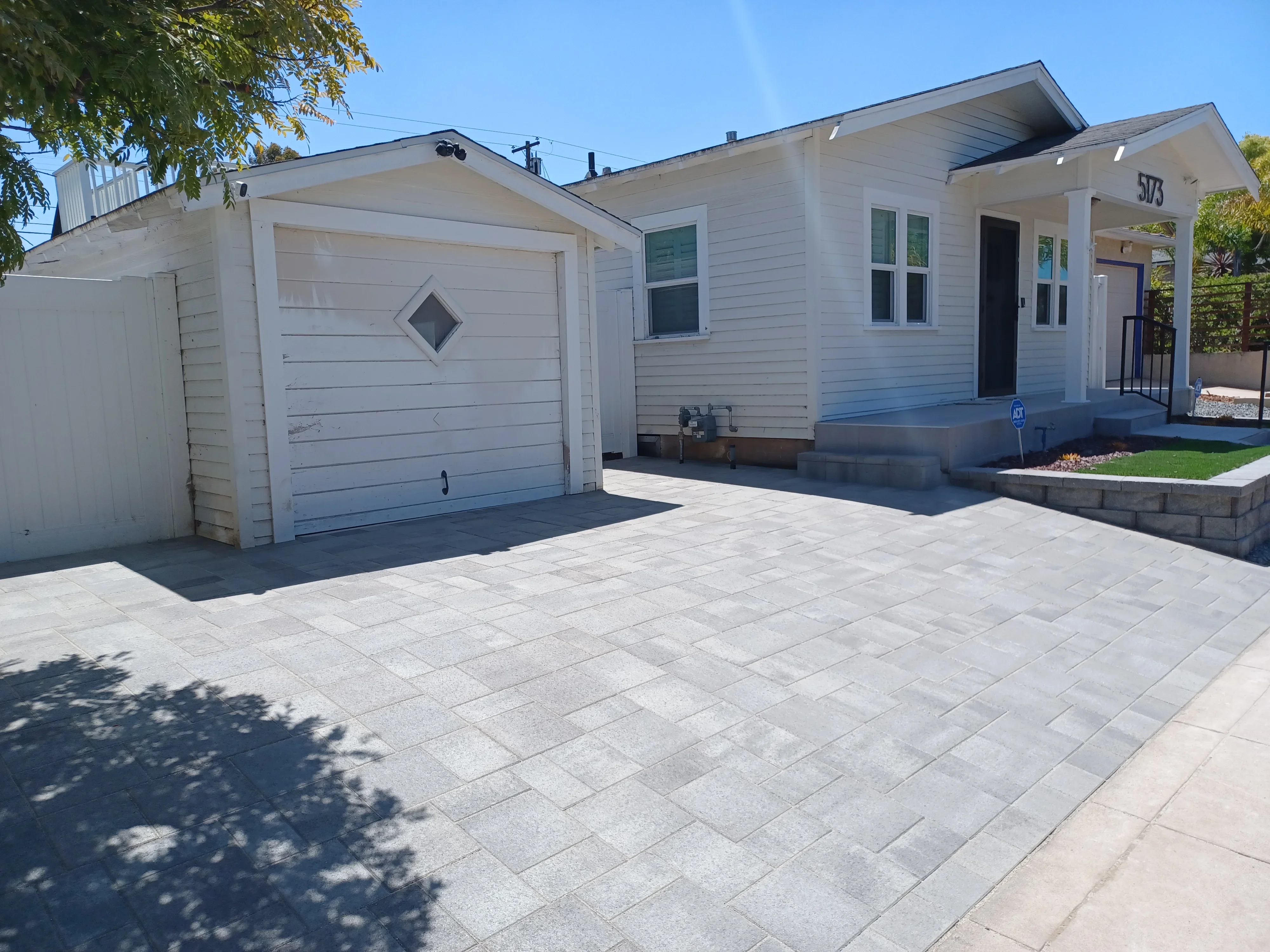 Light gray permeable pavers in running bond pattern with concrete apron and retaining wall edging