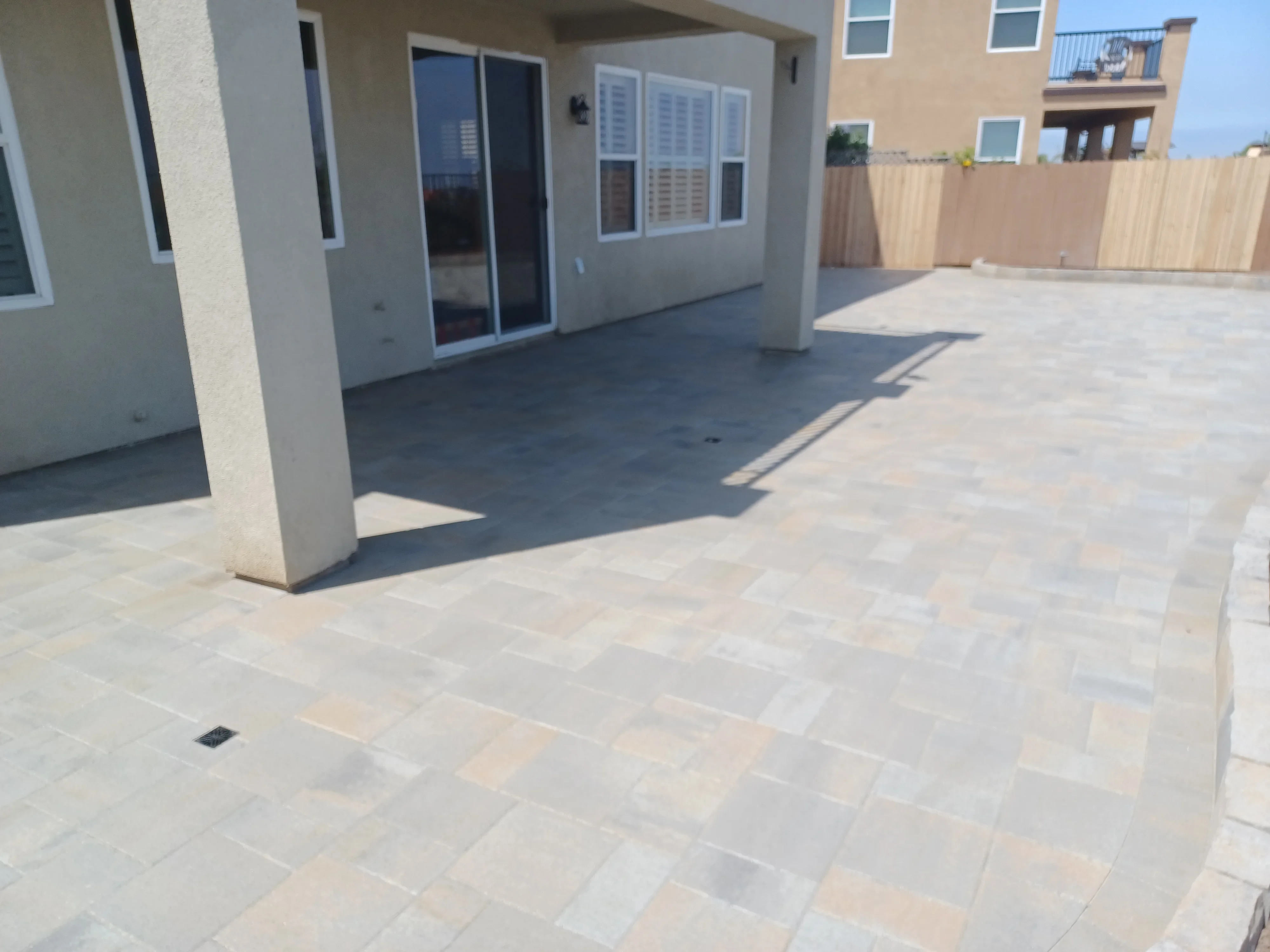 Light porcelain pavers in running bond pattern on rooftop patio with concrete columns