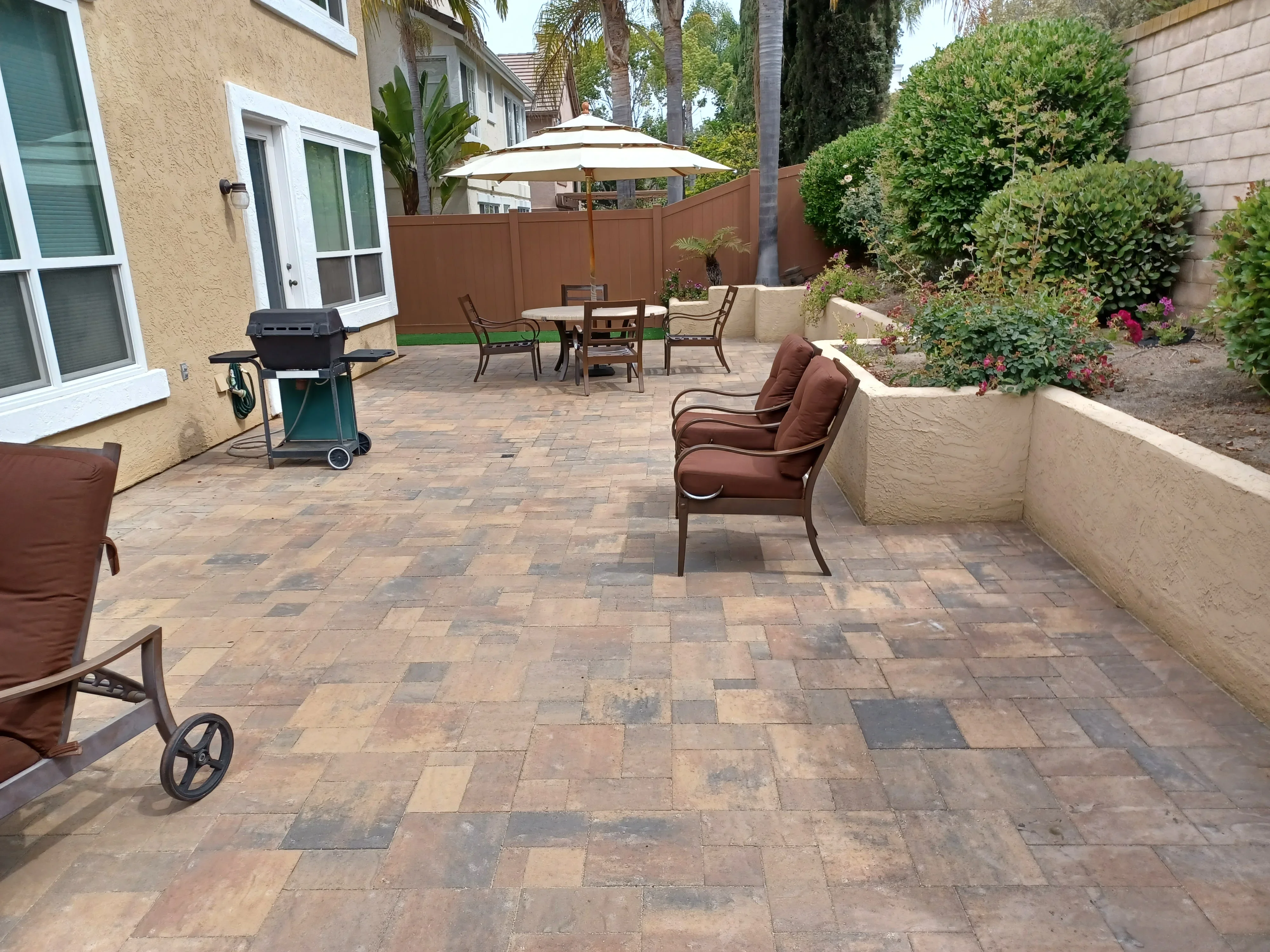 Permeable paver patio with mixed earth-tone pattern and concrete raised planter beds