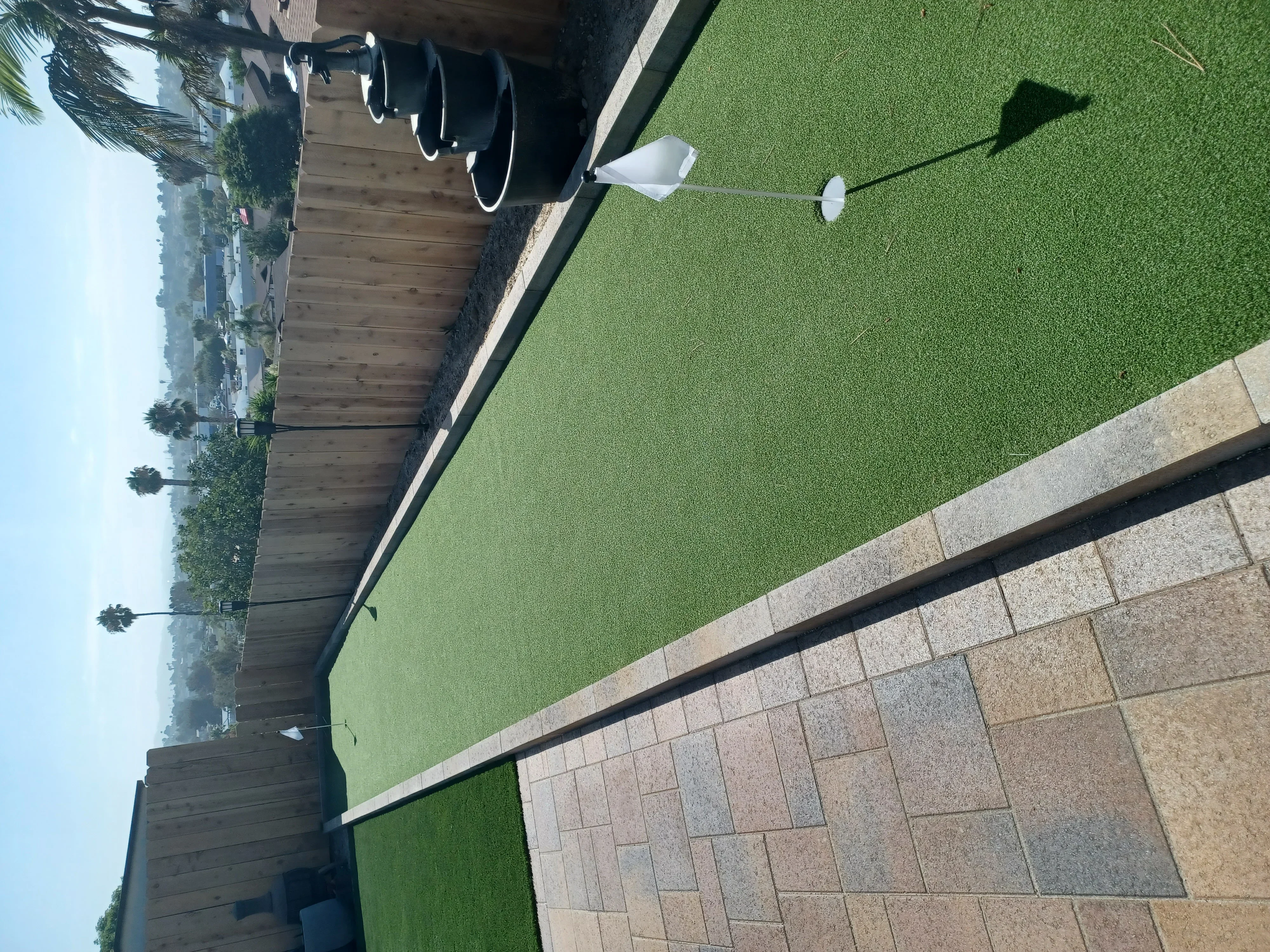 Artificial turf with black metal edging and geometric concrete paver patio installation