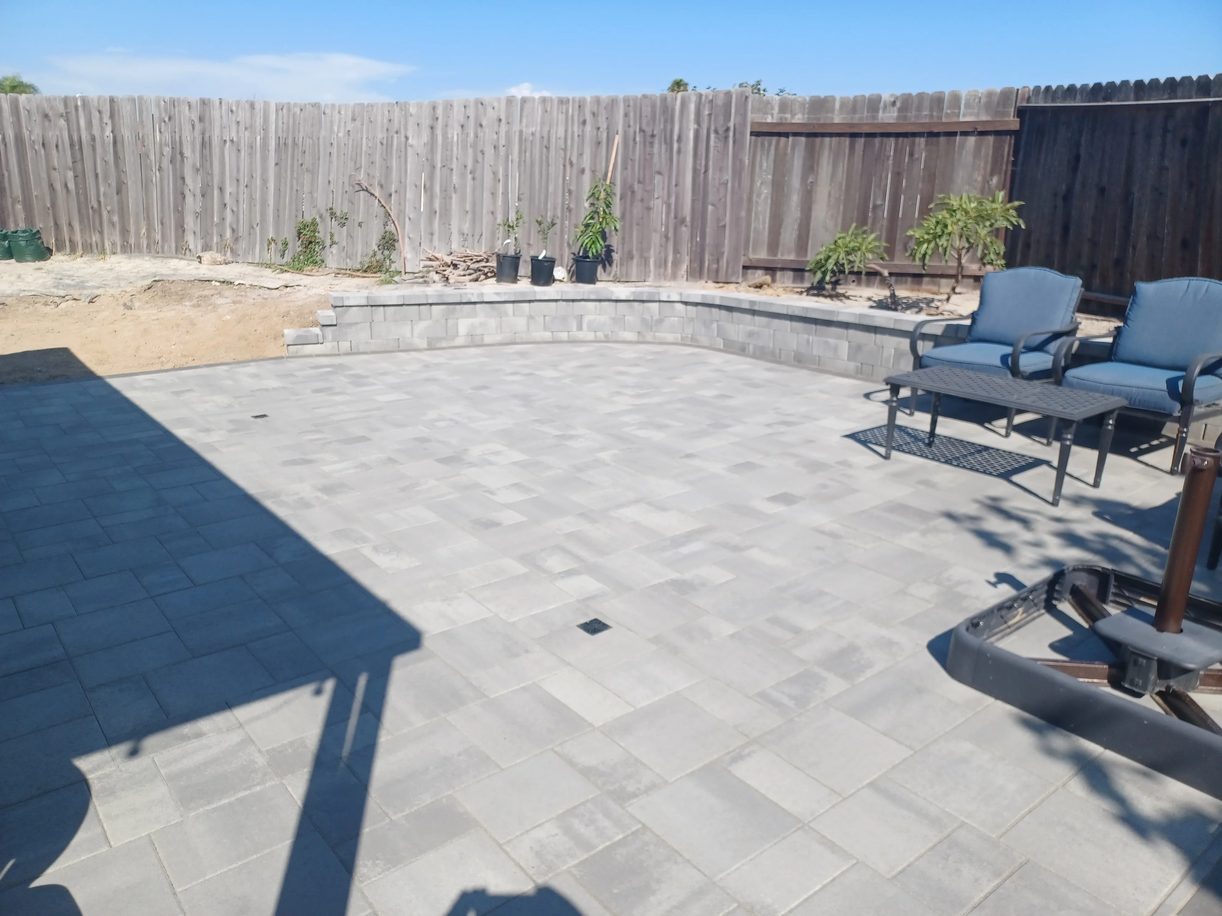 Light gray paver patio with curved retaining wall and seating area