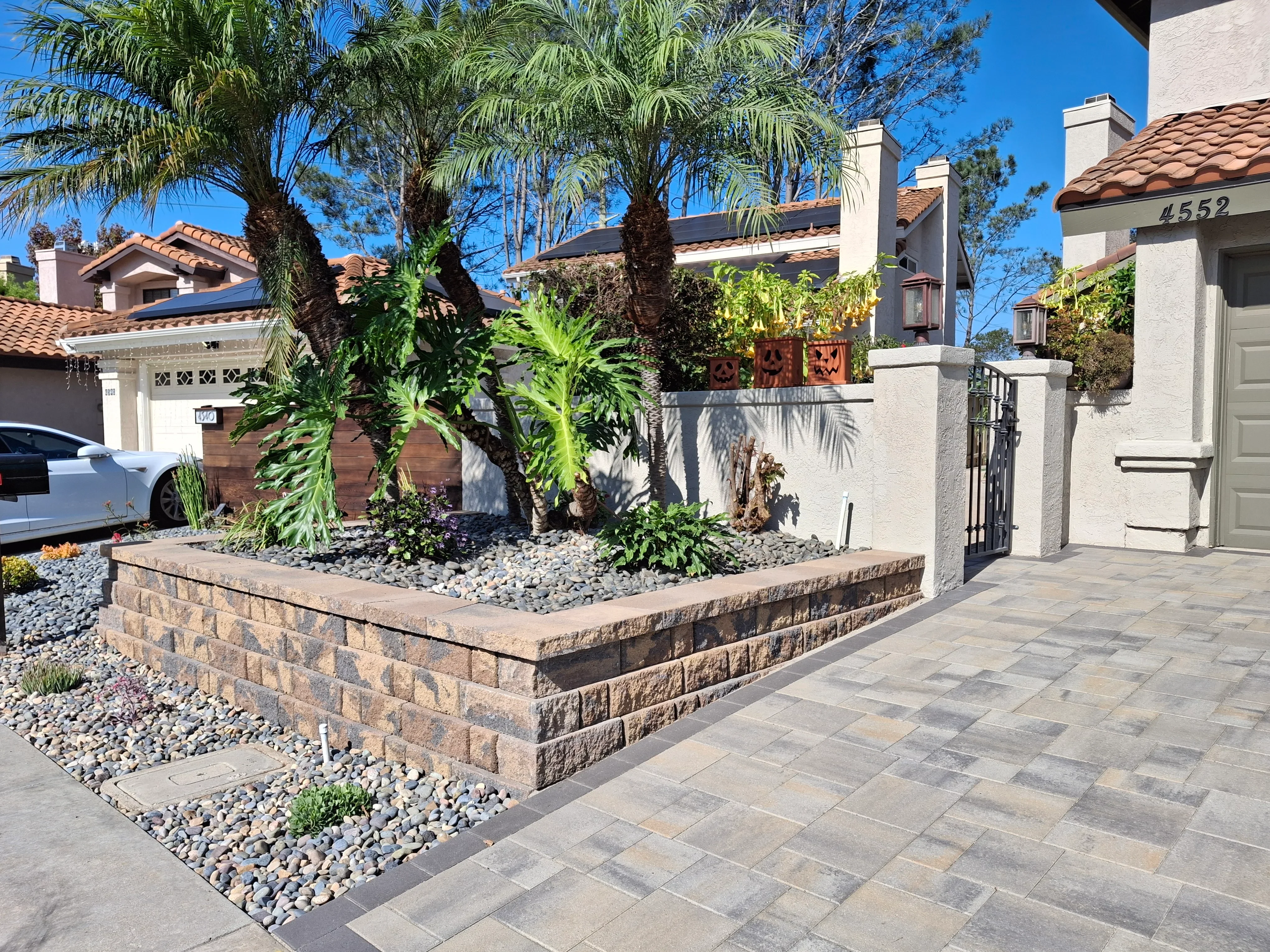 Stacked stone raised planter bed with river rock and paver patio installation