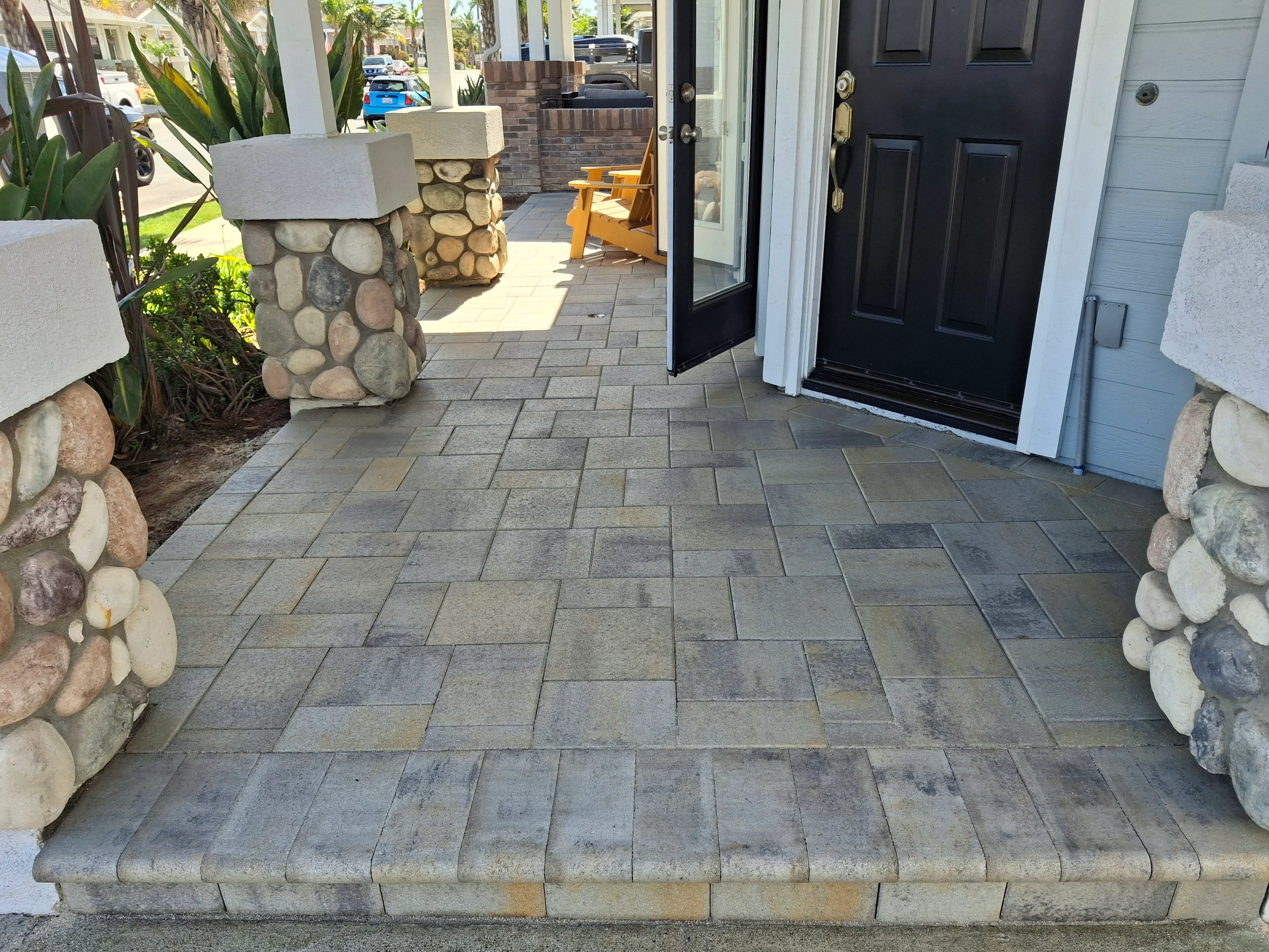 Paver entryway with ashlar pattern and stacked stone pillar planters with concrete caps