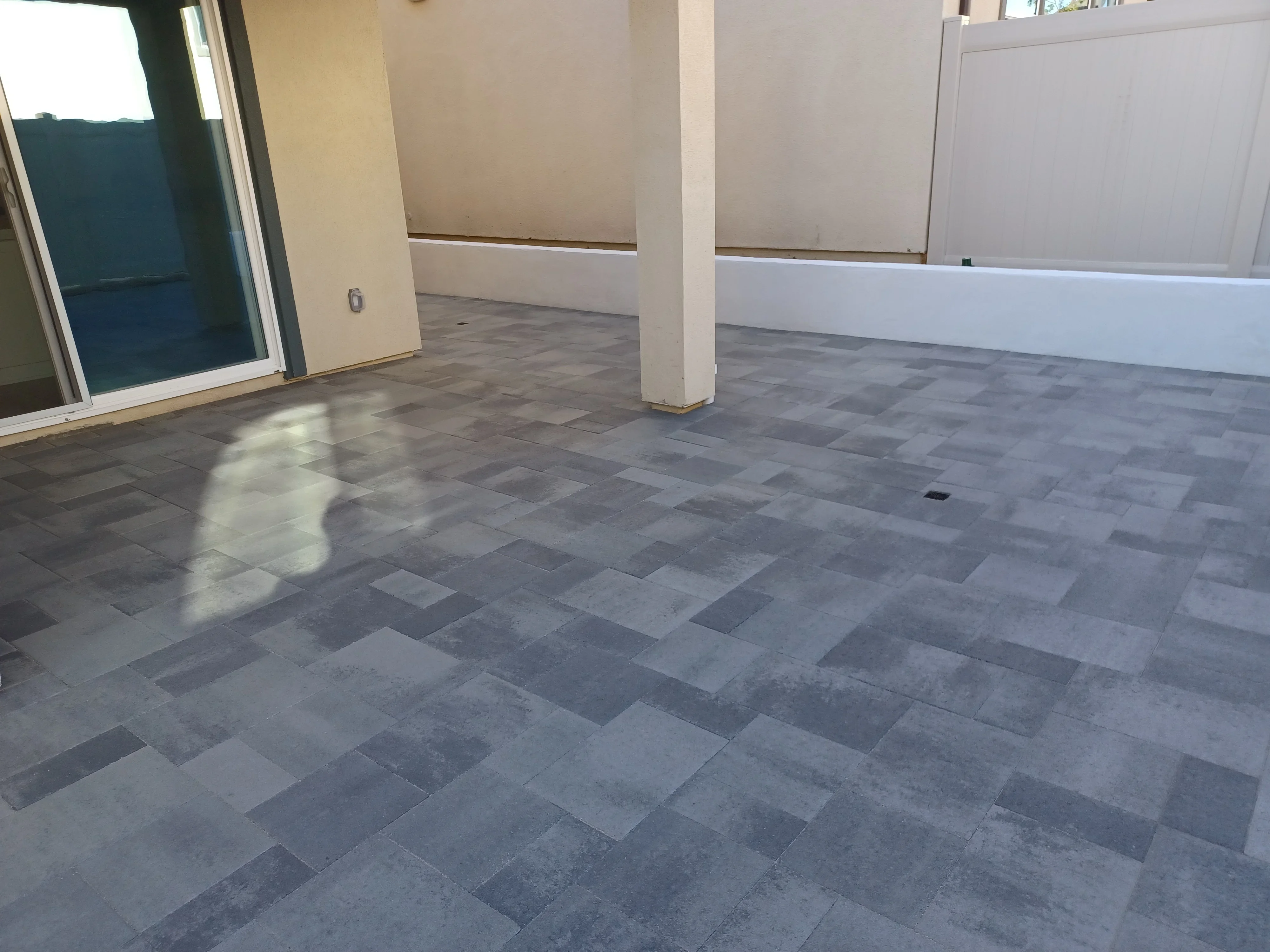Gray and charcoal porcelain pavers in running bond pattern on residential patio with support columns