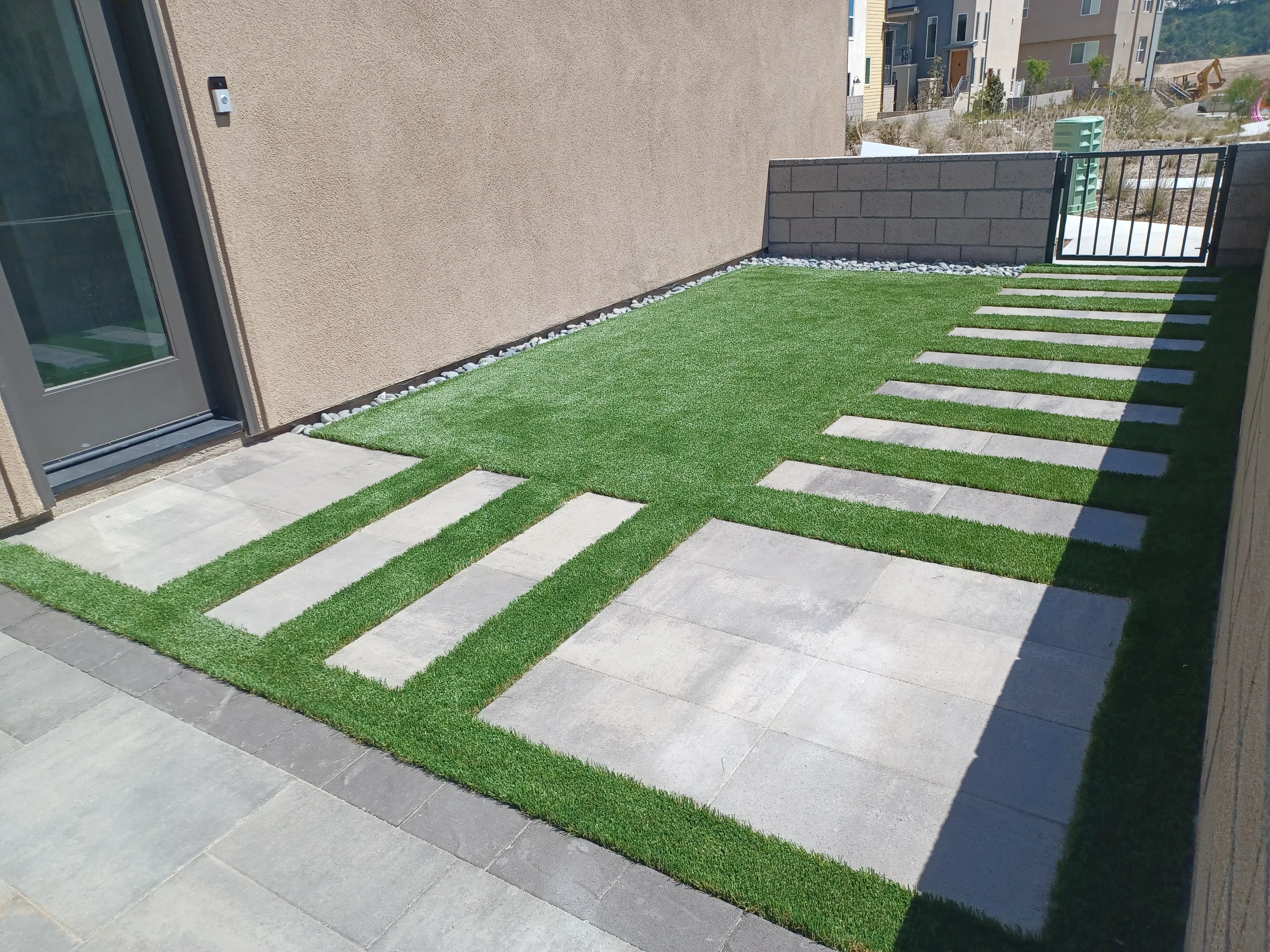 Synthetic turf yard with concrete stepping stones, retaining wall, and metal railing