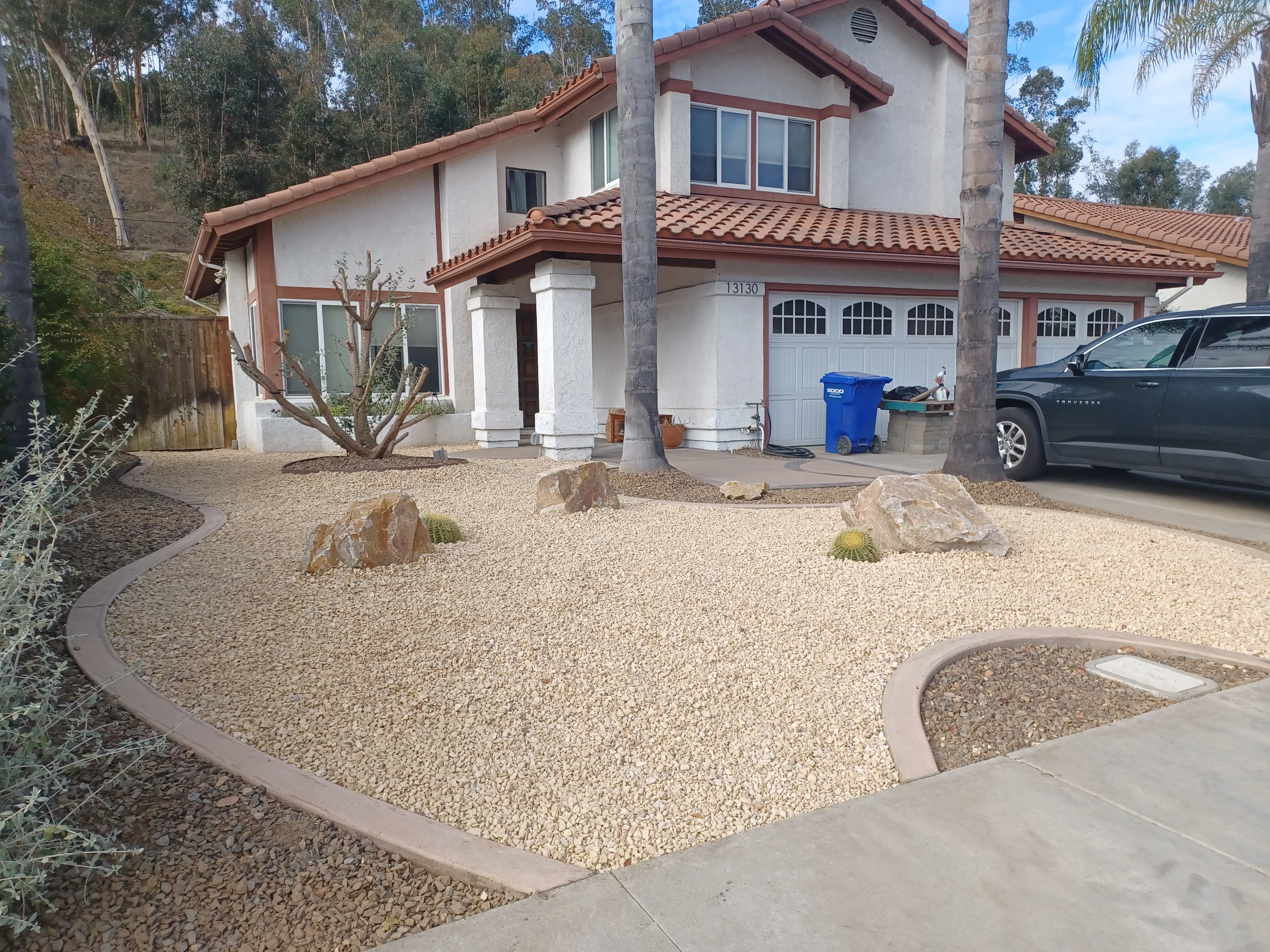 Decomposed granite yard with curved concrete borders, boulders, and desert plantings