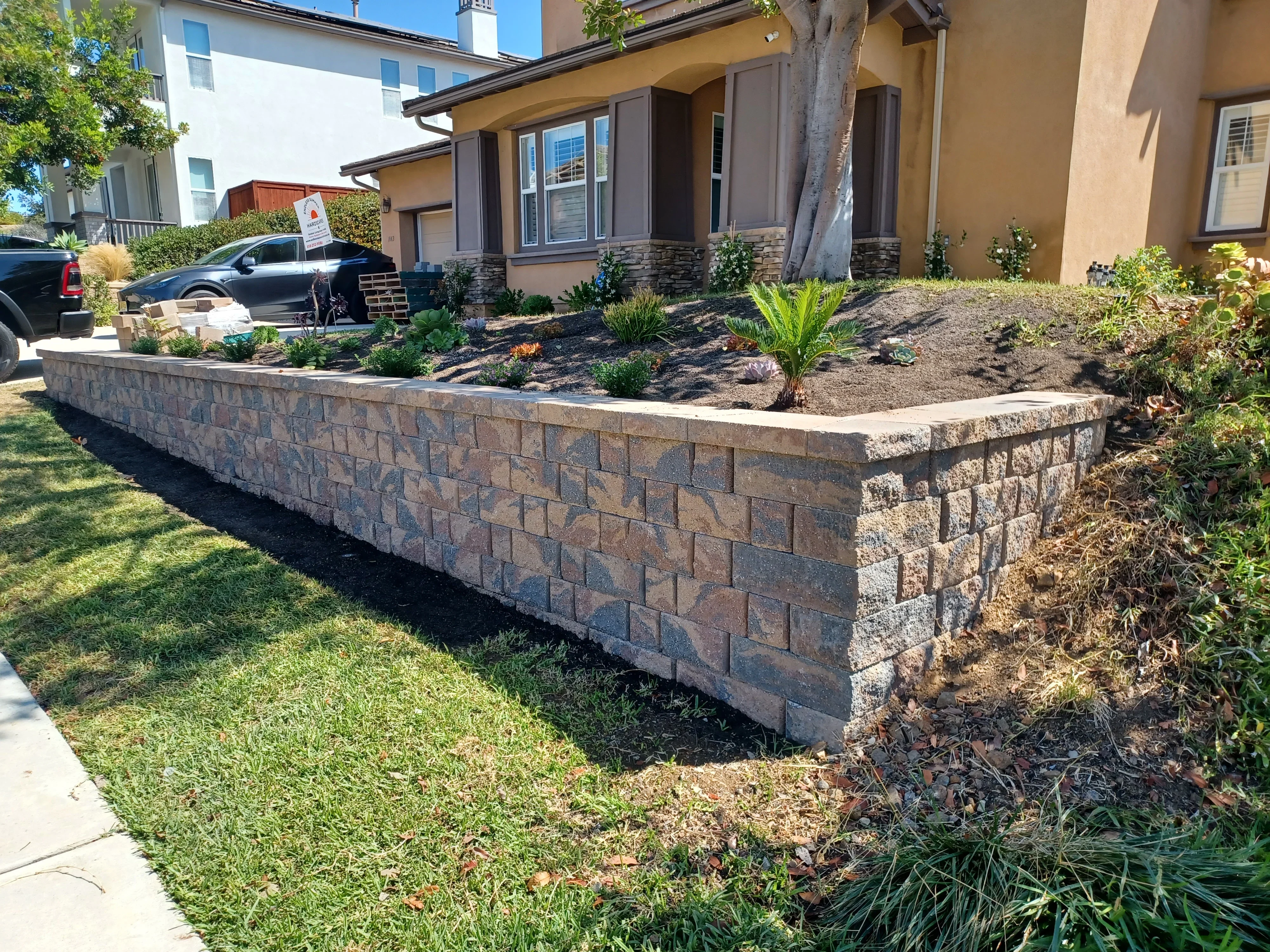 Stacked stone retaining wall with curved design and landscape planting beds