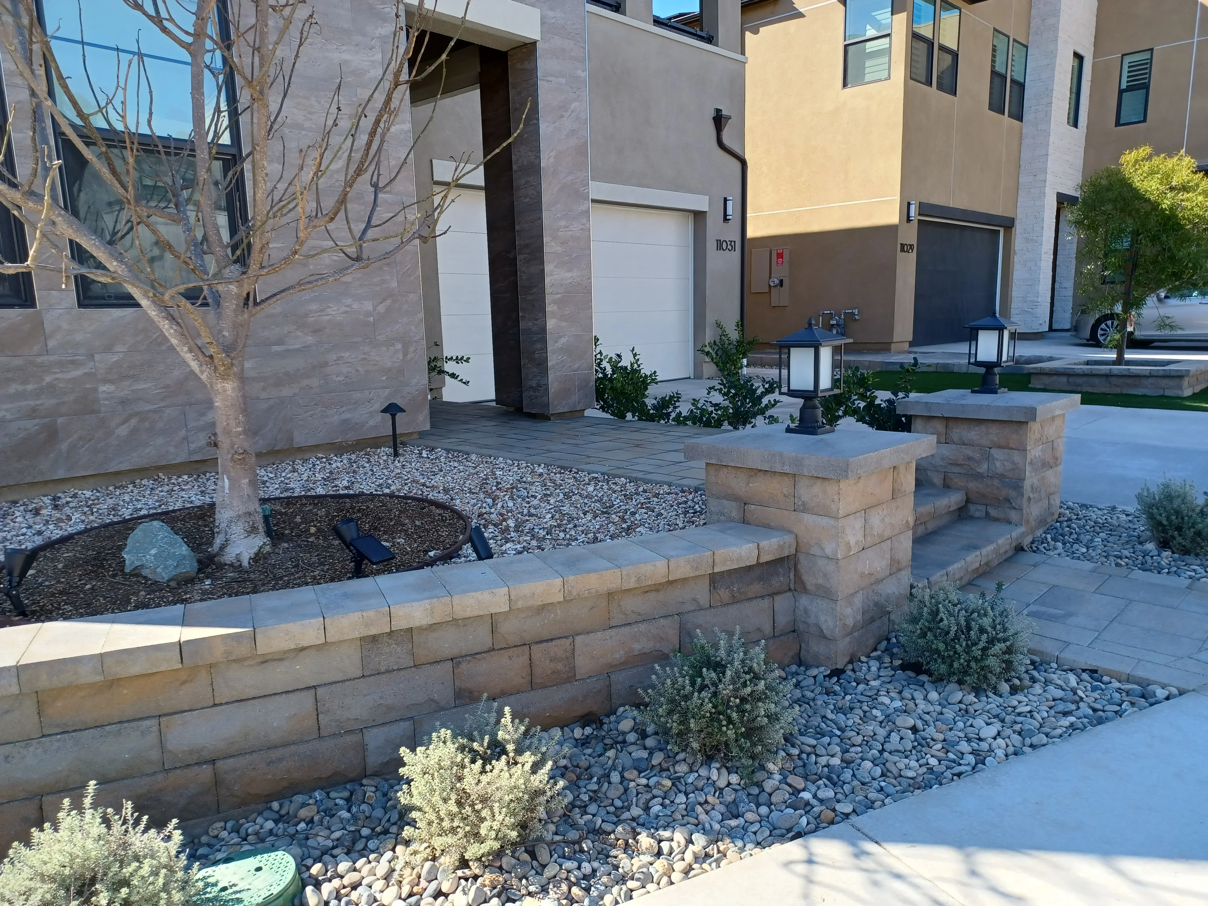 Stacked stone retaining walls with tiered seating, gravel beds, and paver courtyard