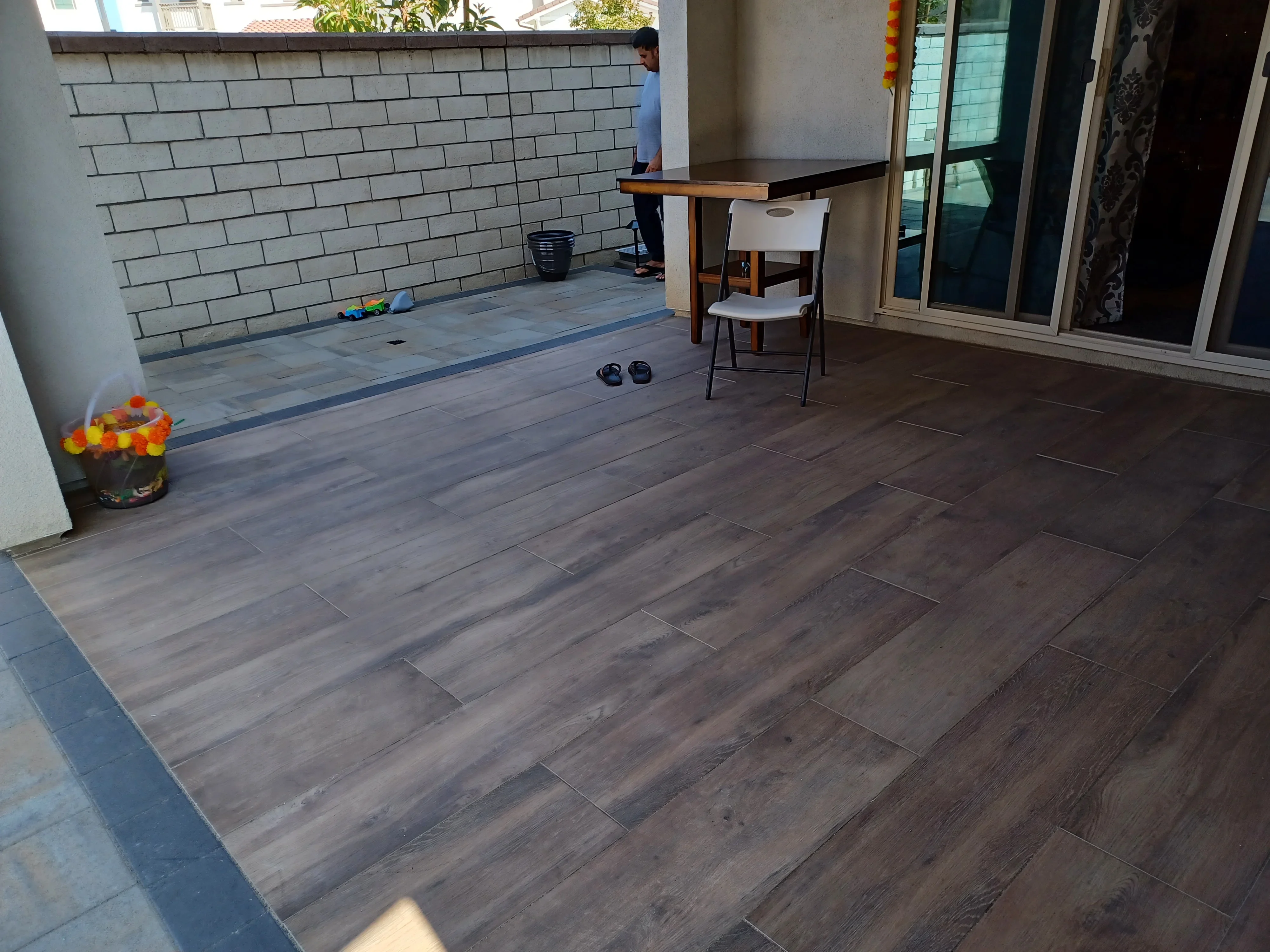 Wood-look porcelain pavers in running bond pattern with blue-gray accent stripe on residential patio