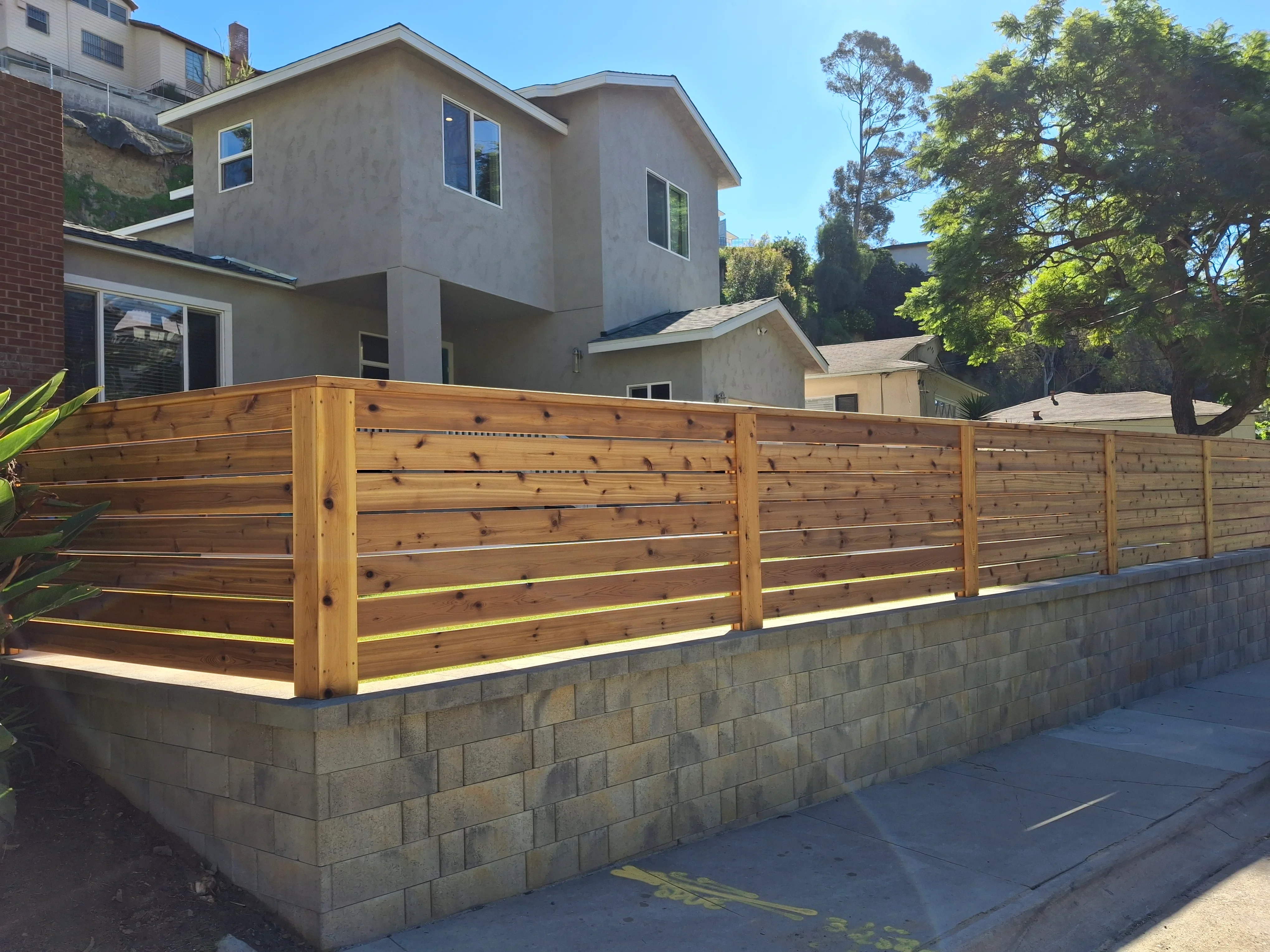 Horizontal cedar wood fence on concrete block retaining wall with integrated lighting