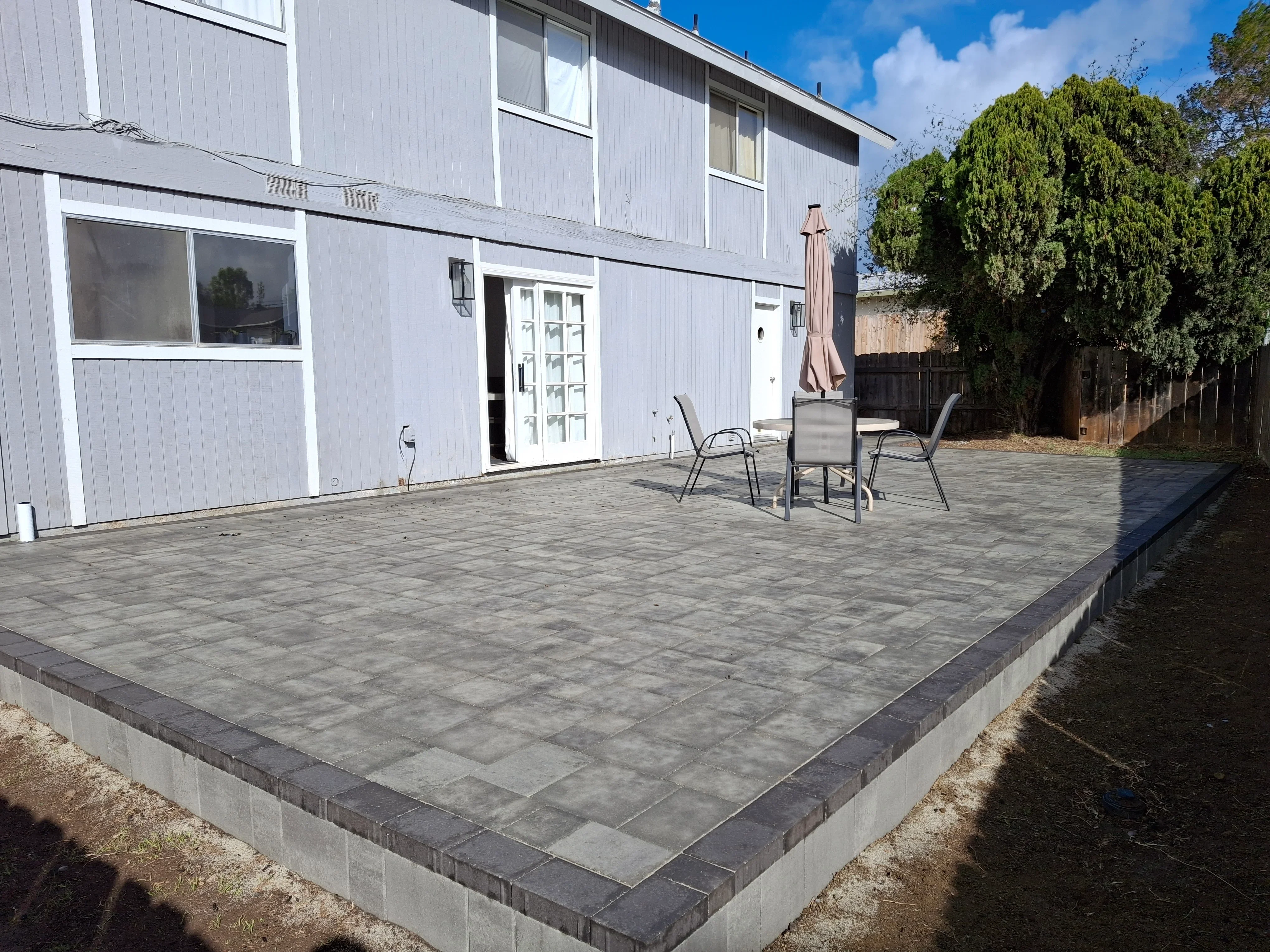 Gray concrete paver patio with dark border edging and concrete foundation