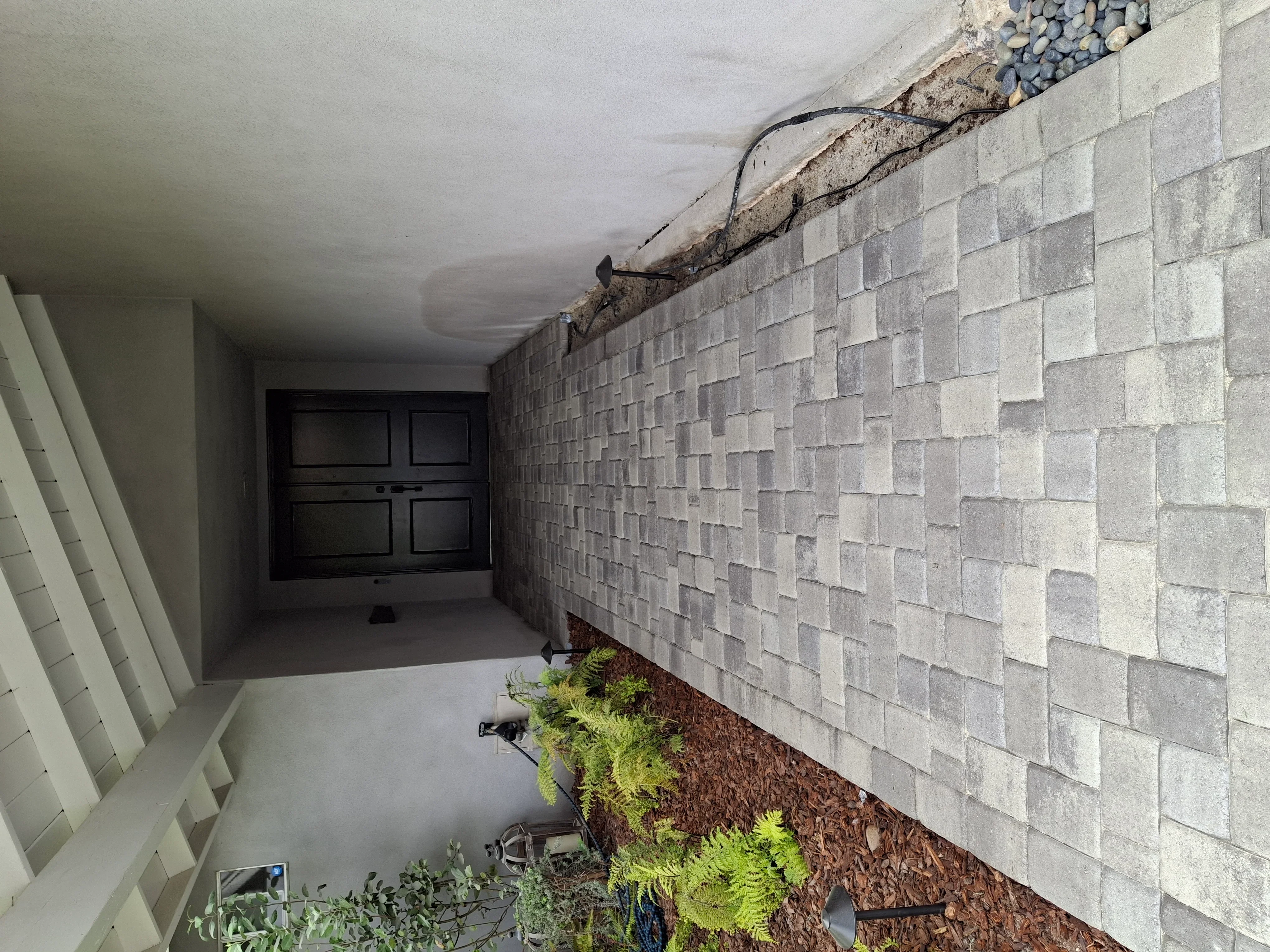 Concrete block retaining wall with staggered pattern, drainage gravel, and landscape fabric installation