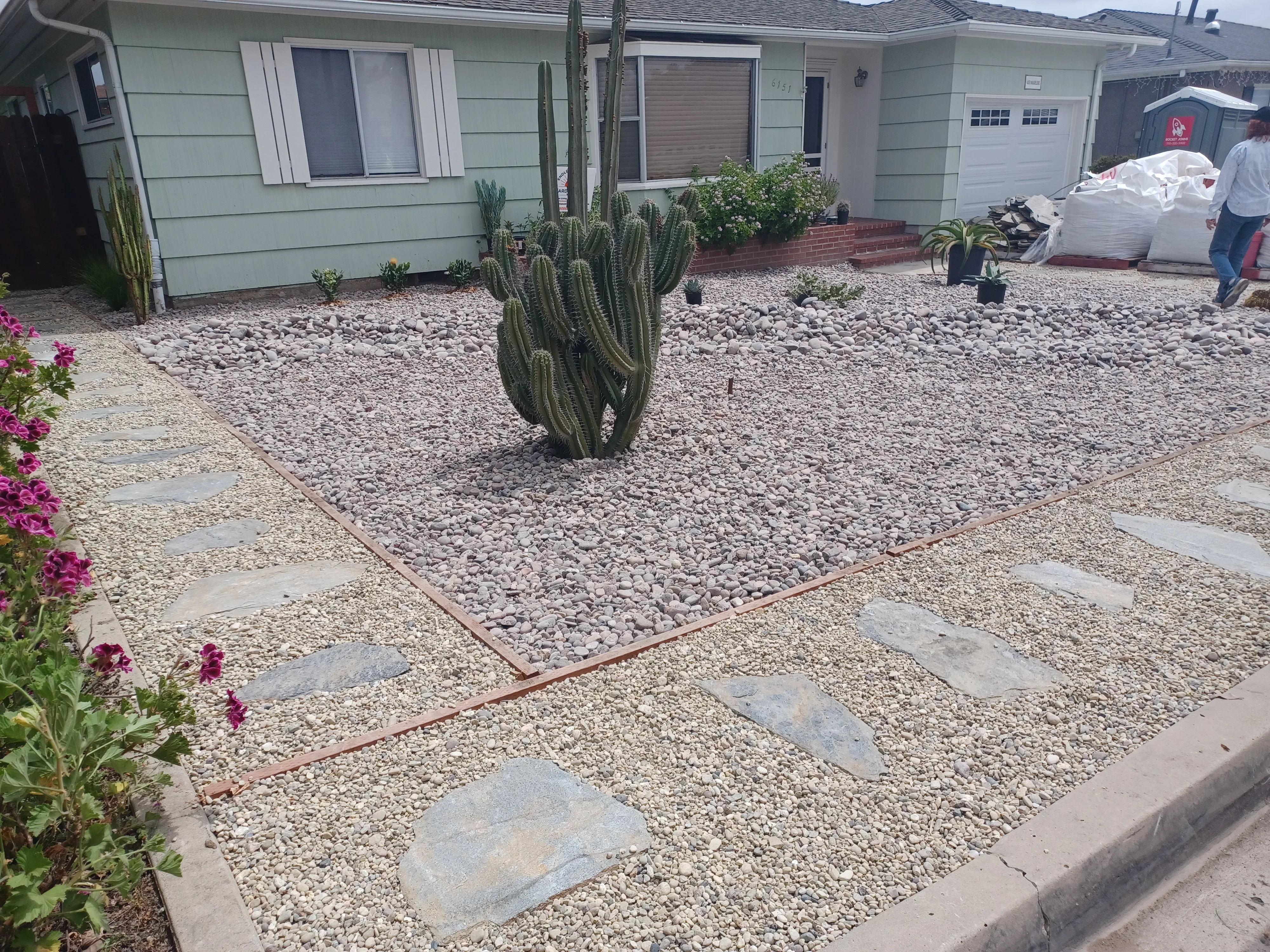 Decomposed granite yard with river rock bed, steel edging, and stone stepping stone pathway