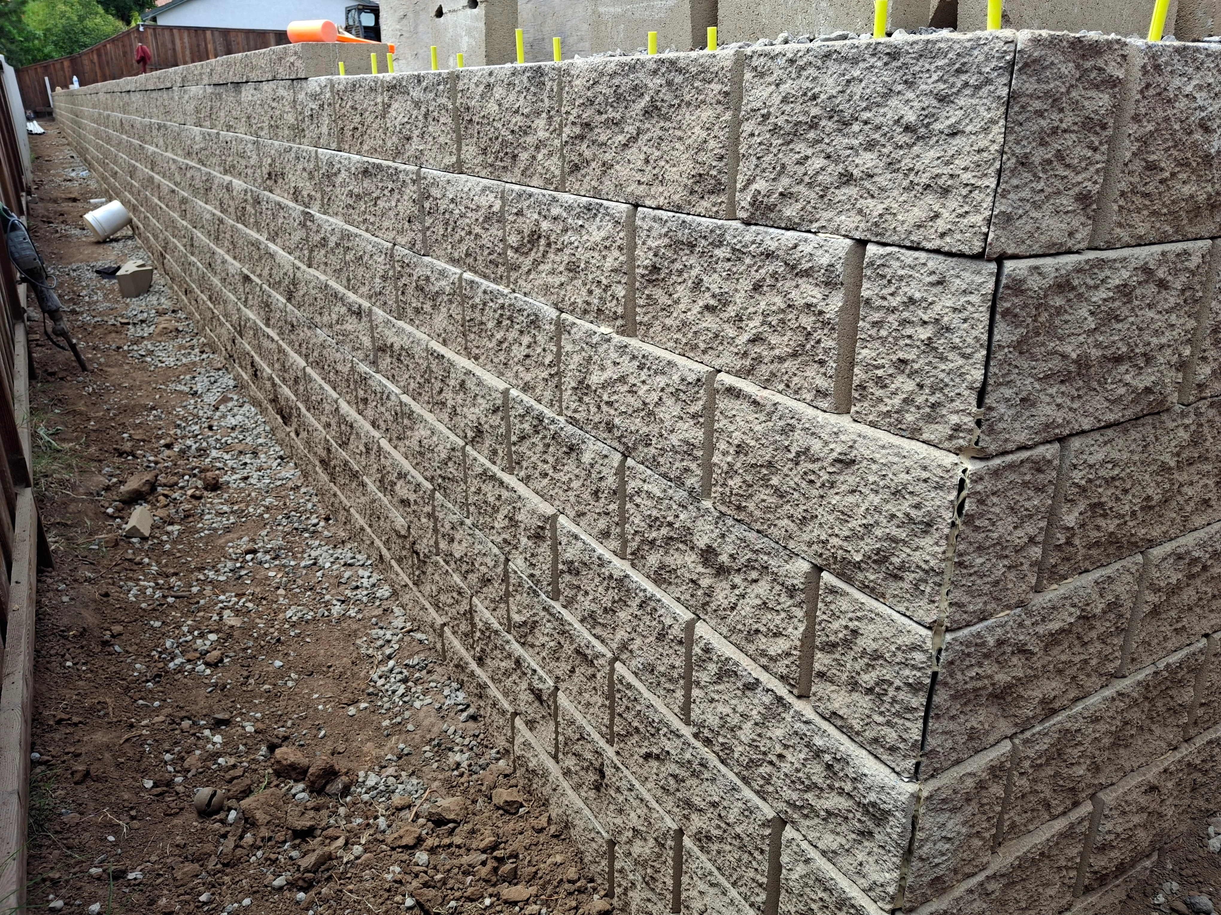 Stacked concrete retaining wall blocks with steel reinforcement pins and gravel base