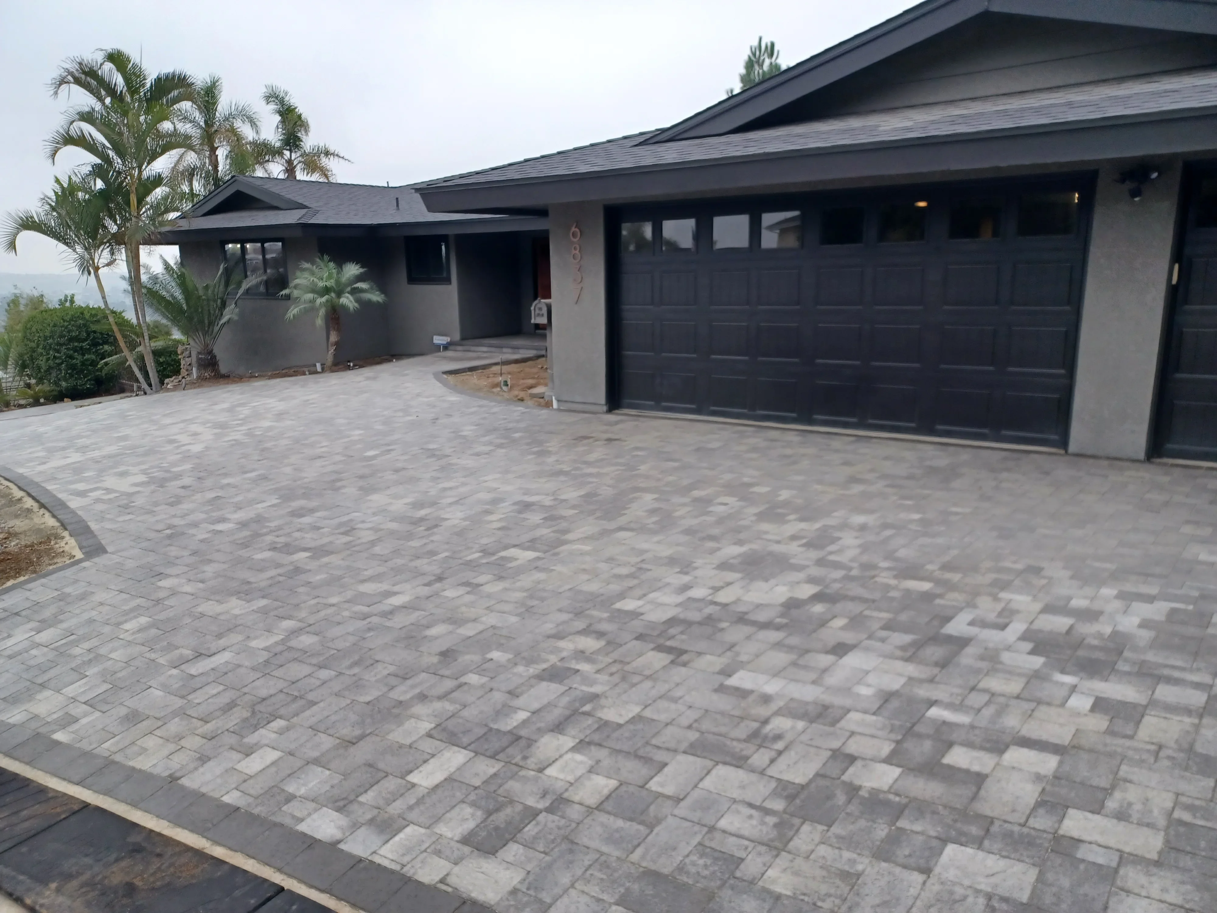 Gray and charcoal concrete pavers in herringbone pattern on residential driveway with dual garage
