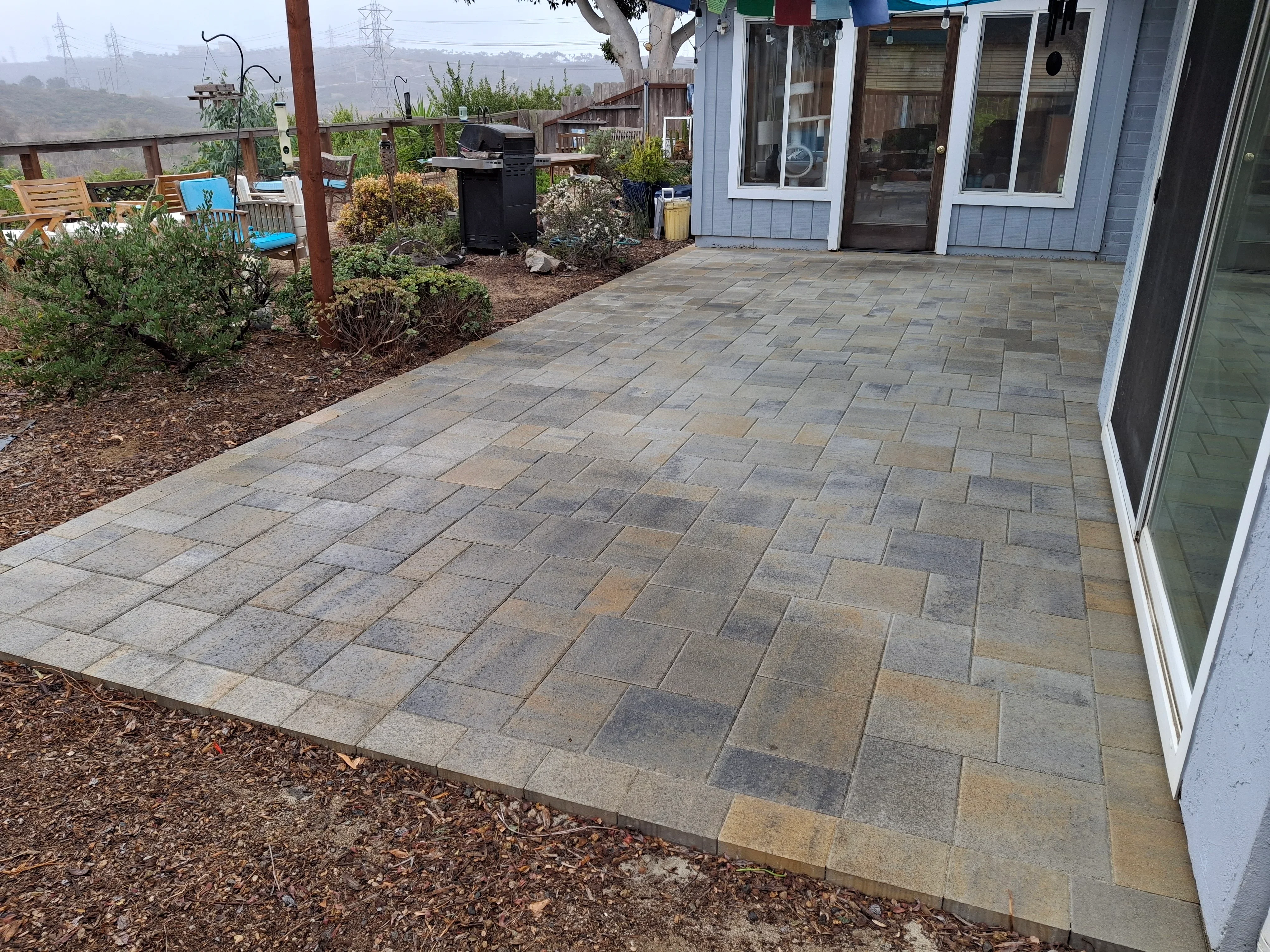 Multi-toned concrete paver patio in herringbone pattern adjacent to residence