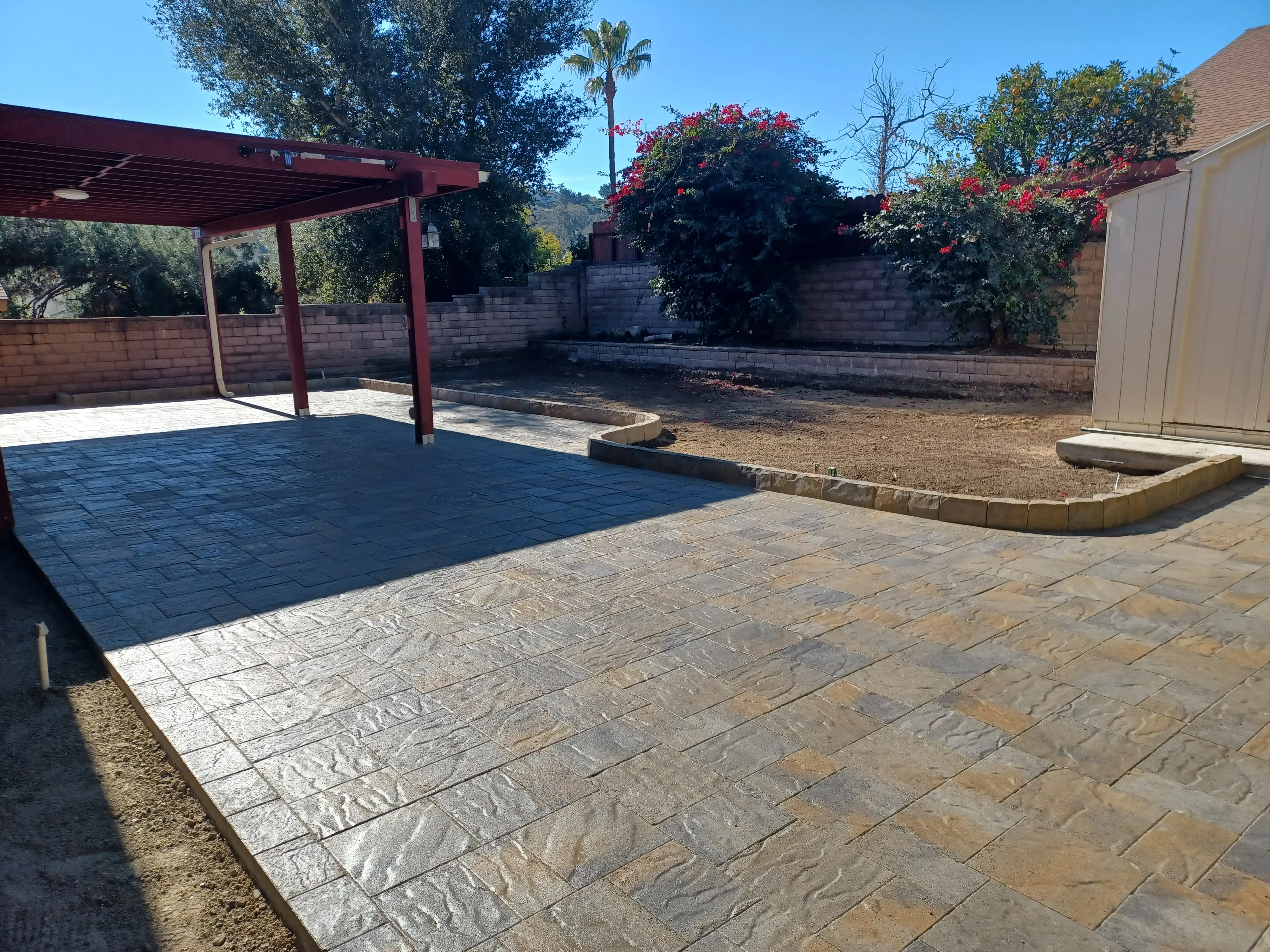 Stamped concrete patio with wood grain pattern and red steel pergola structure