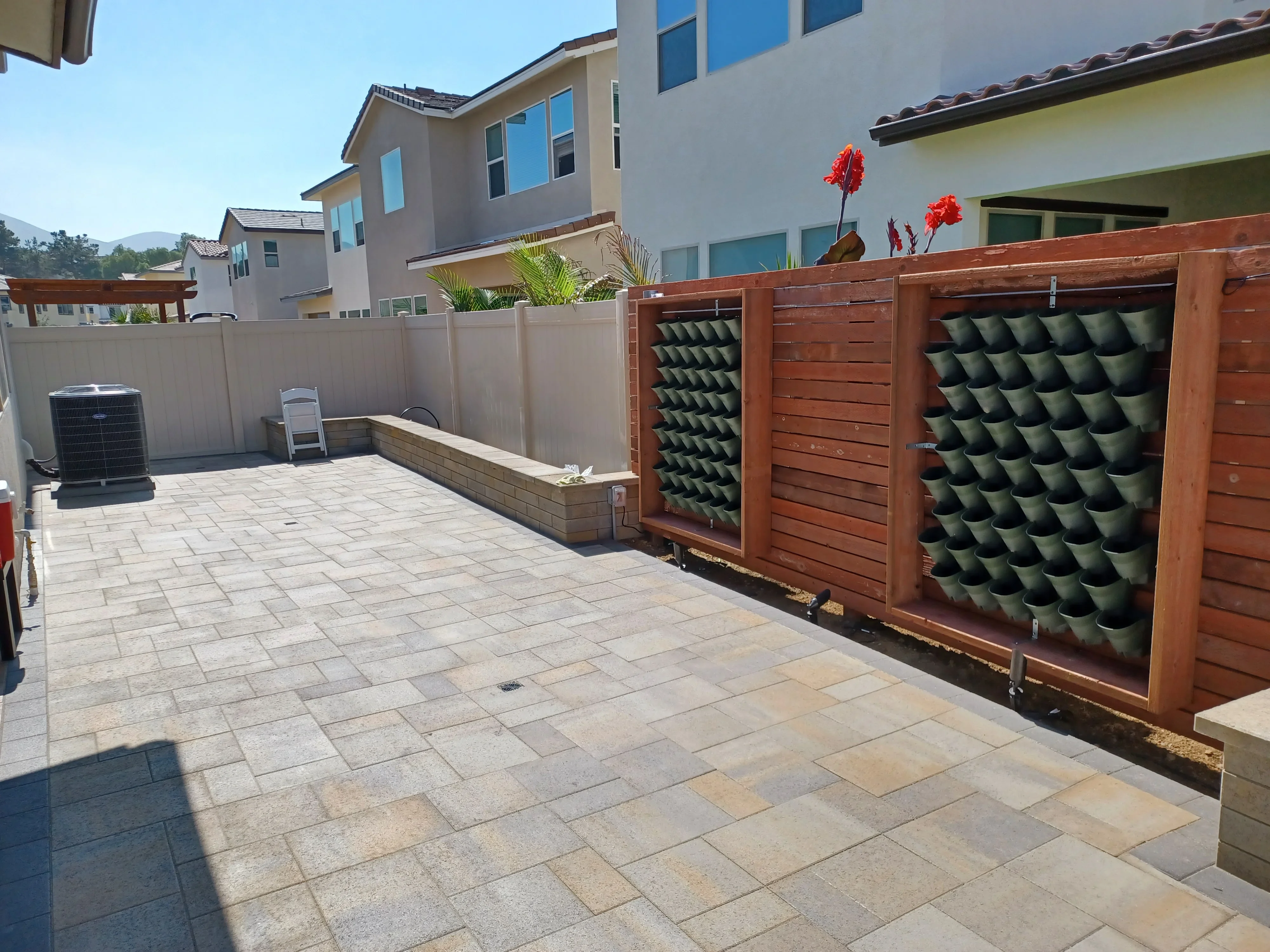 Paver patio with composite fence, green wall panels, and stone planter wall