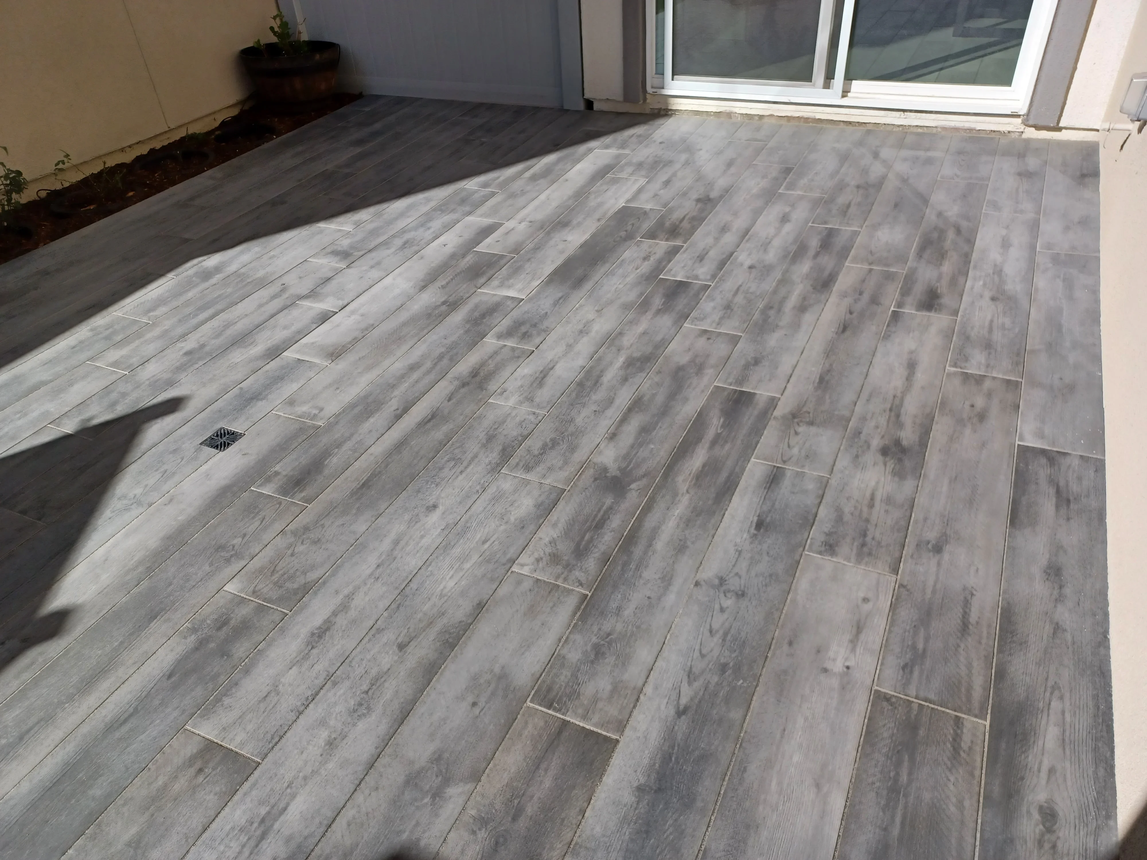 Gray wood-look porcelain pavers in running bond pattern on residential patio