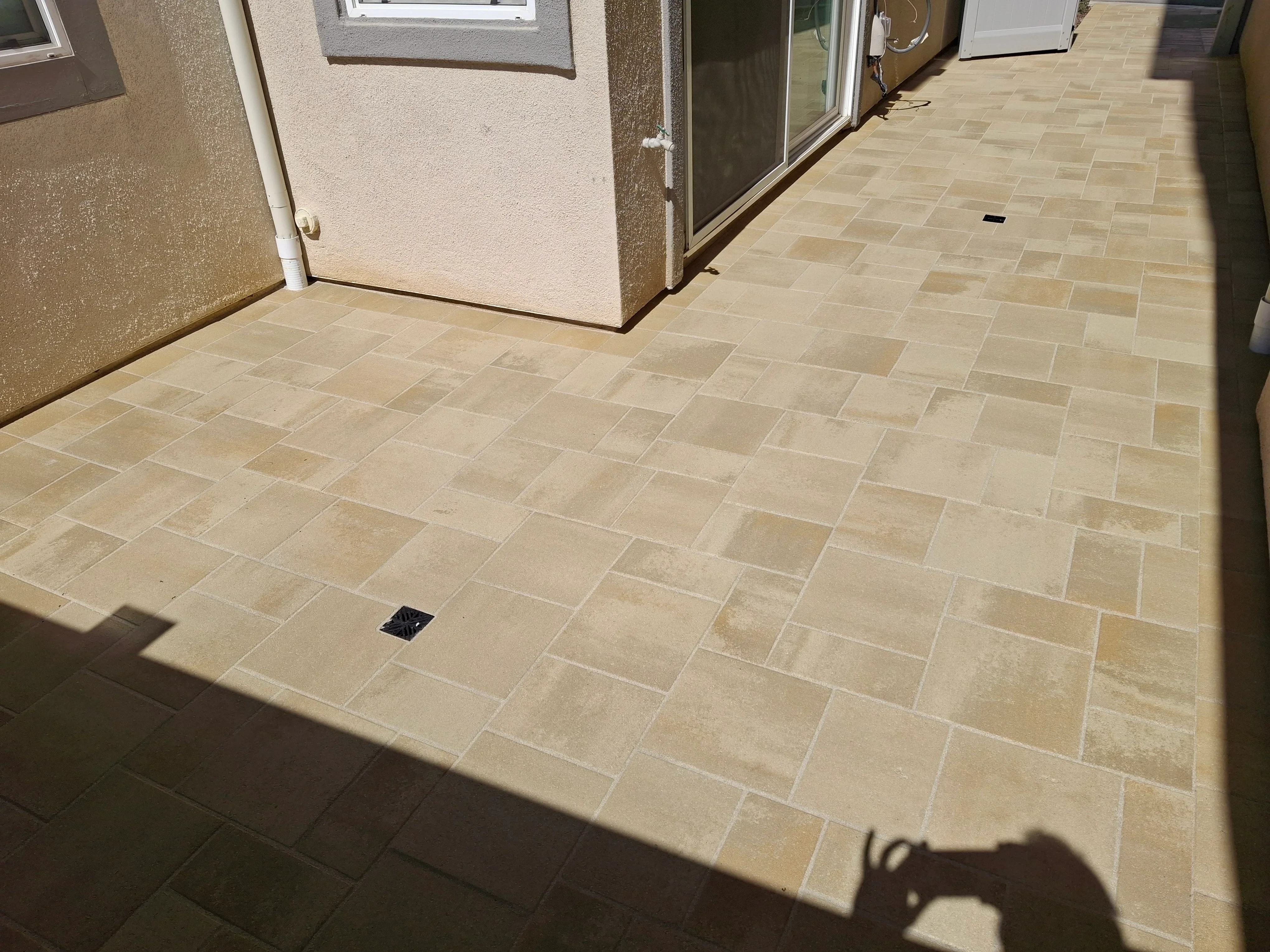 Travertine pavers in running bond pattern with drainage inlet, neutral tones