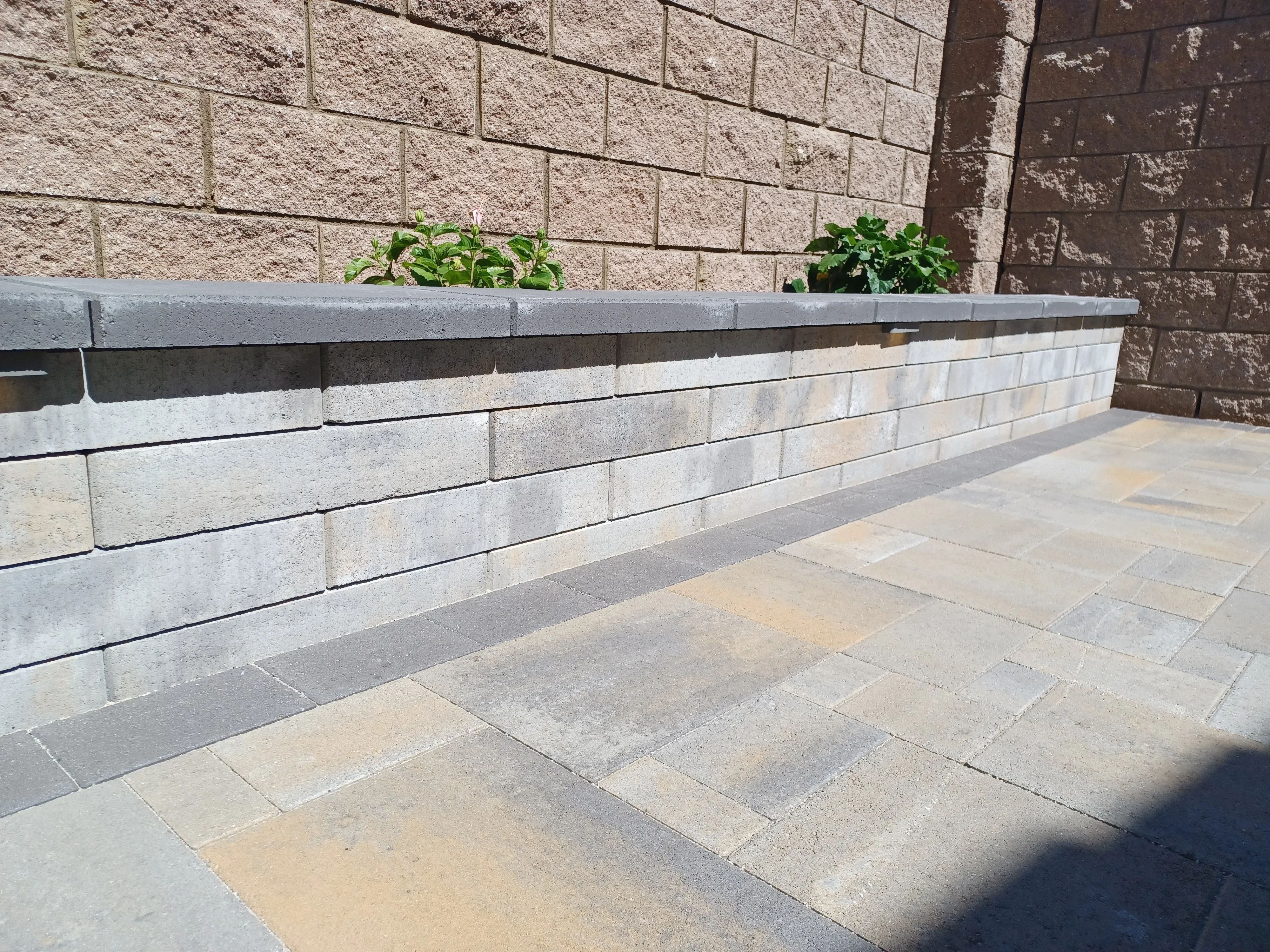 Gray and white segmental concrete retaining wall with planter cap and concrete paver patio