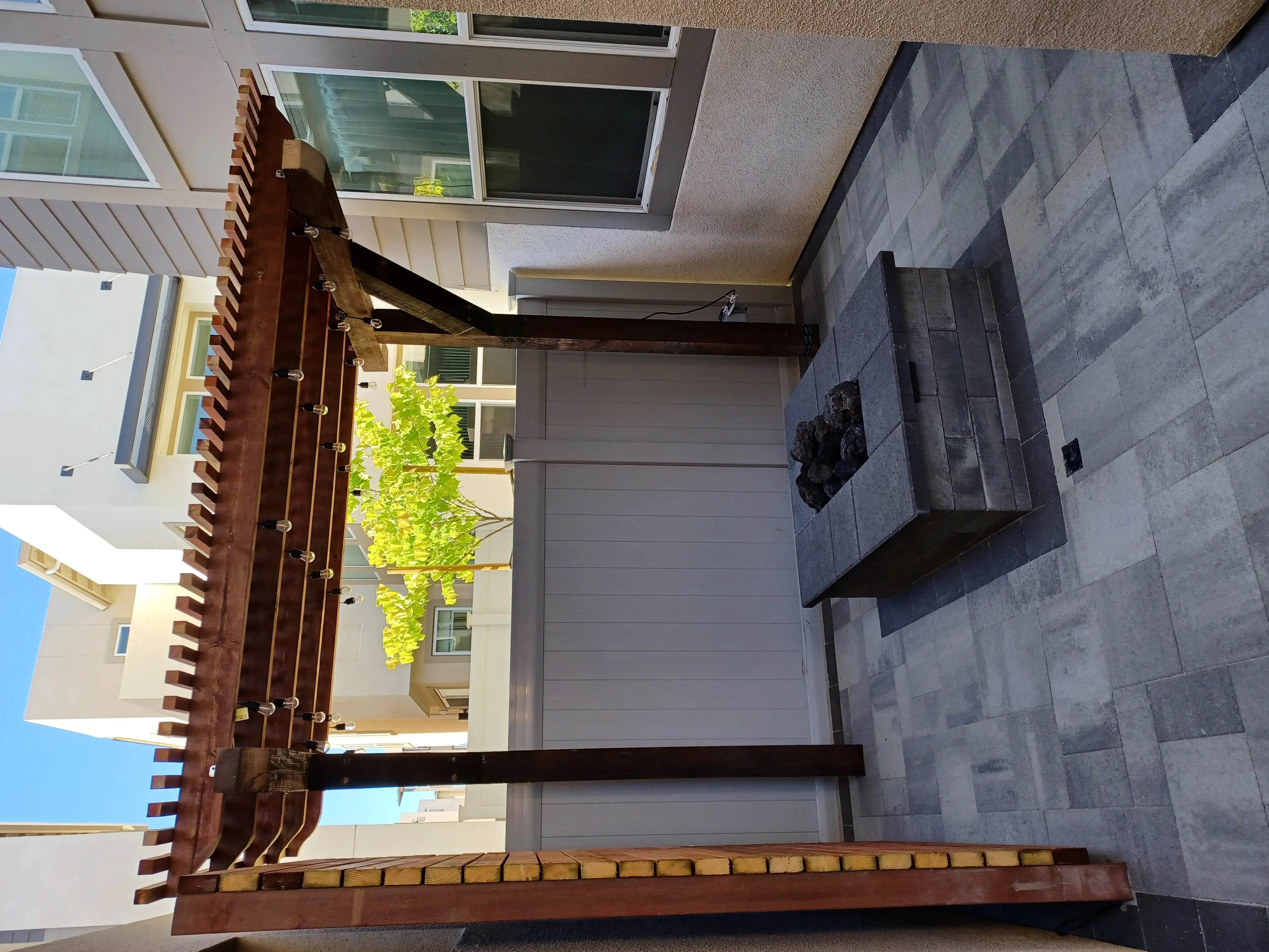 Gray porcelain pavers, metal pergola, and wooden privacy screen in residential courtyard
