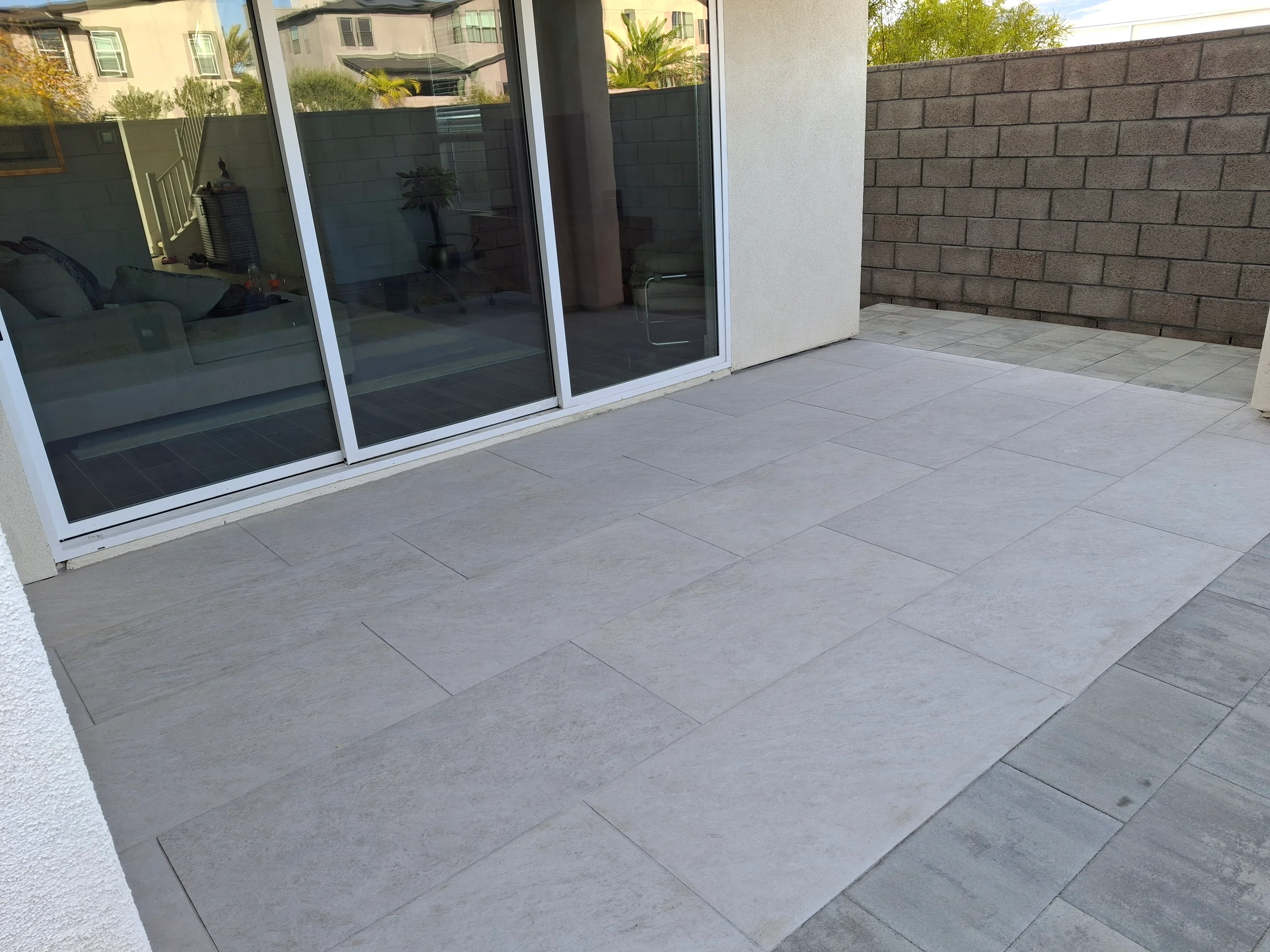 Light gray porcelain paver patio with running bond pattern and concrete block wall