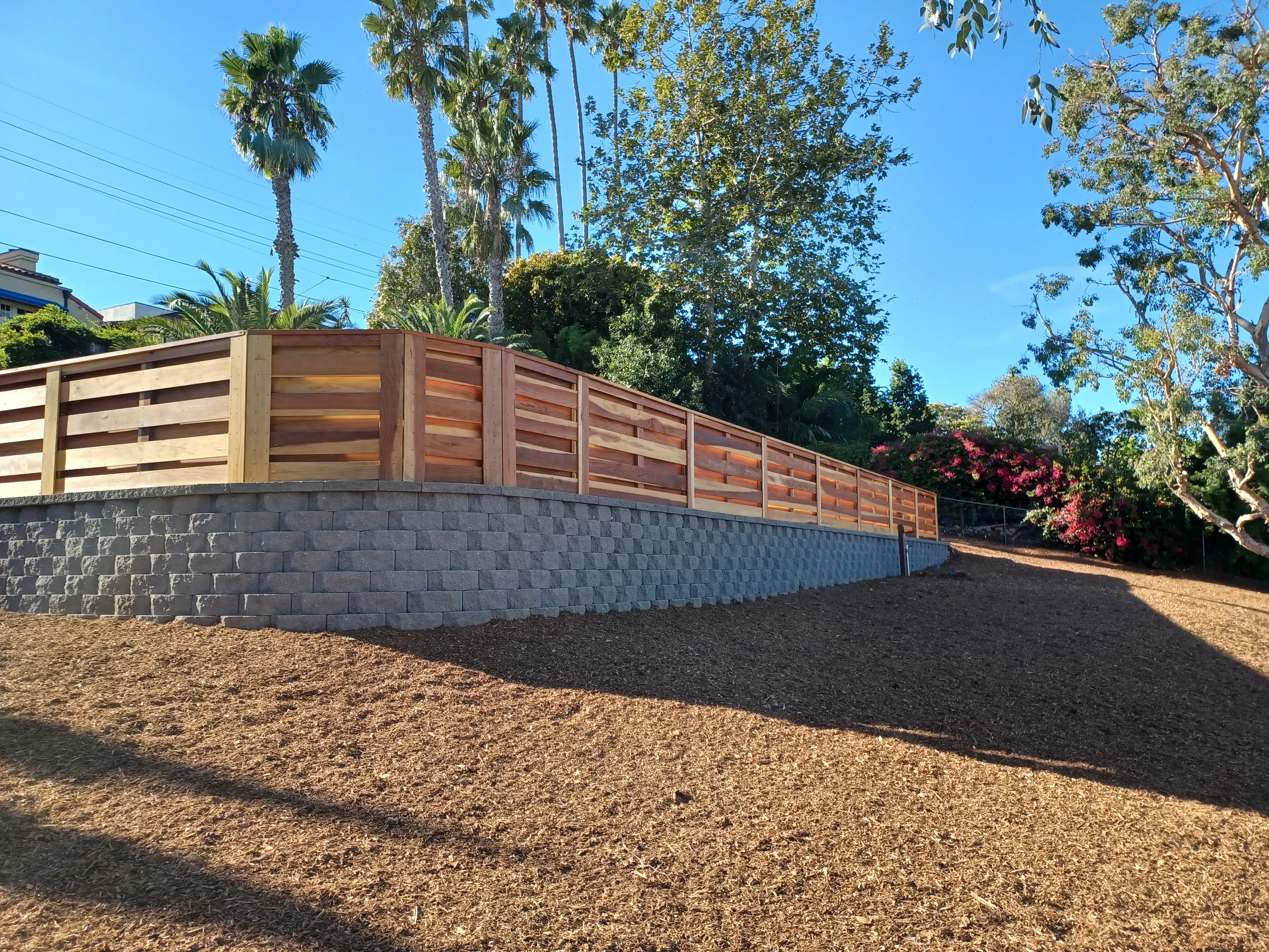 Horizontal wood fence with concrete block retaining wall and gravel base