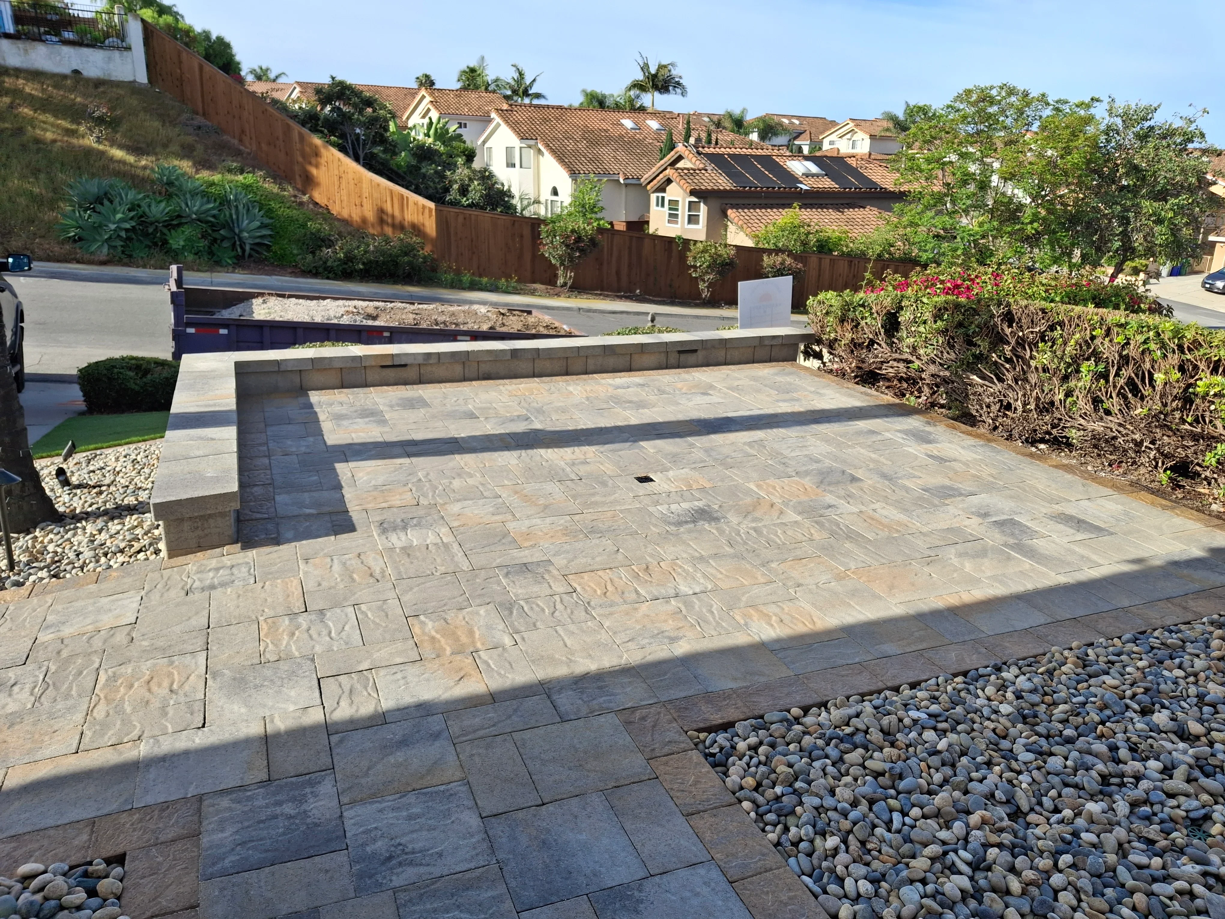 Permeable stone paver driveway with geometric pattern and concrete retaining wall