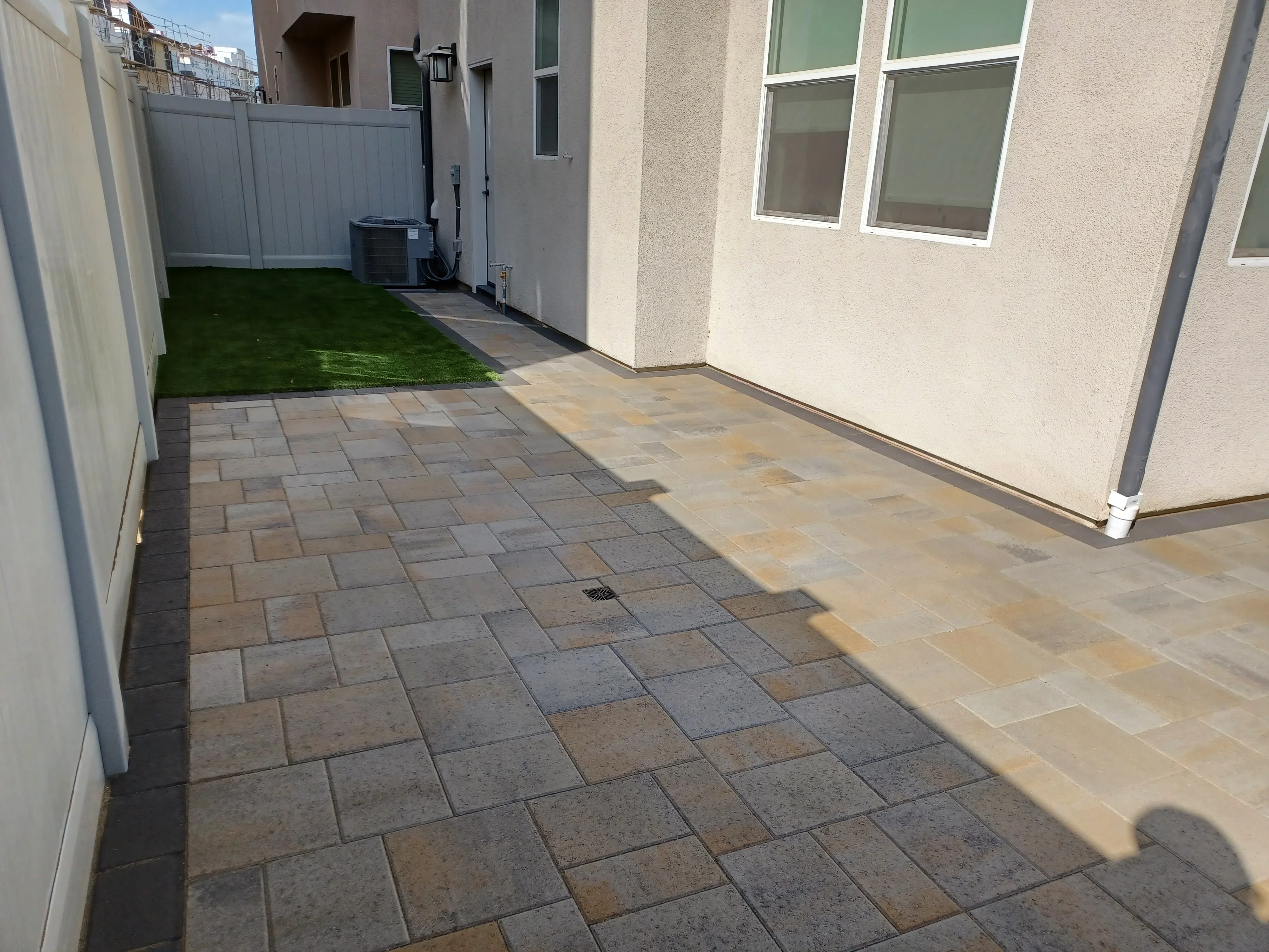Mixed-tone permeable pavers in running bond pattern with synthetic turf and composite fence