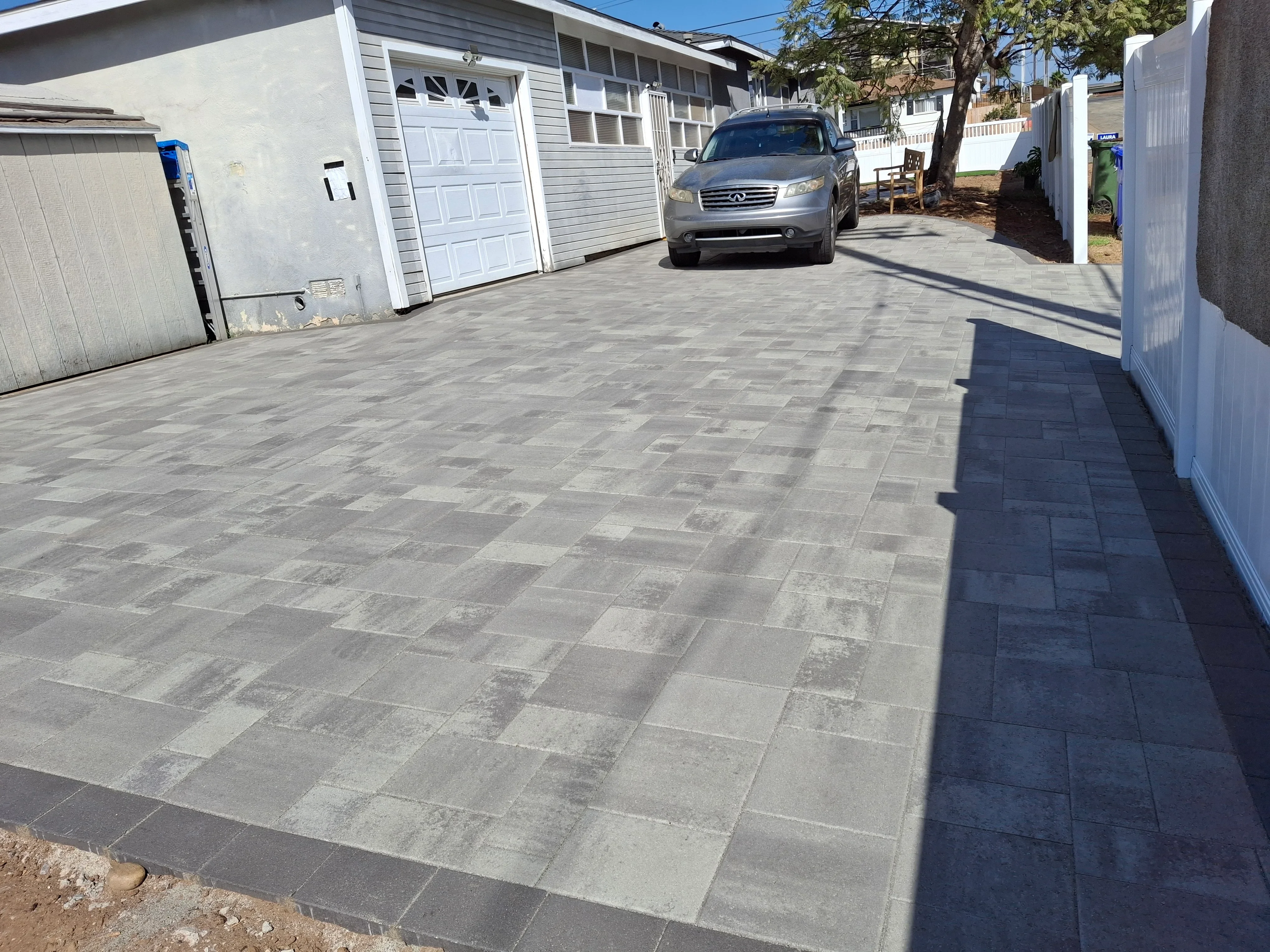 Gray permeable pavers installed in running bond pattern on residential driveway with vehicle parked on surface