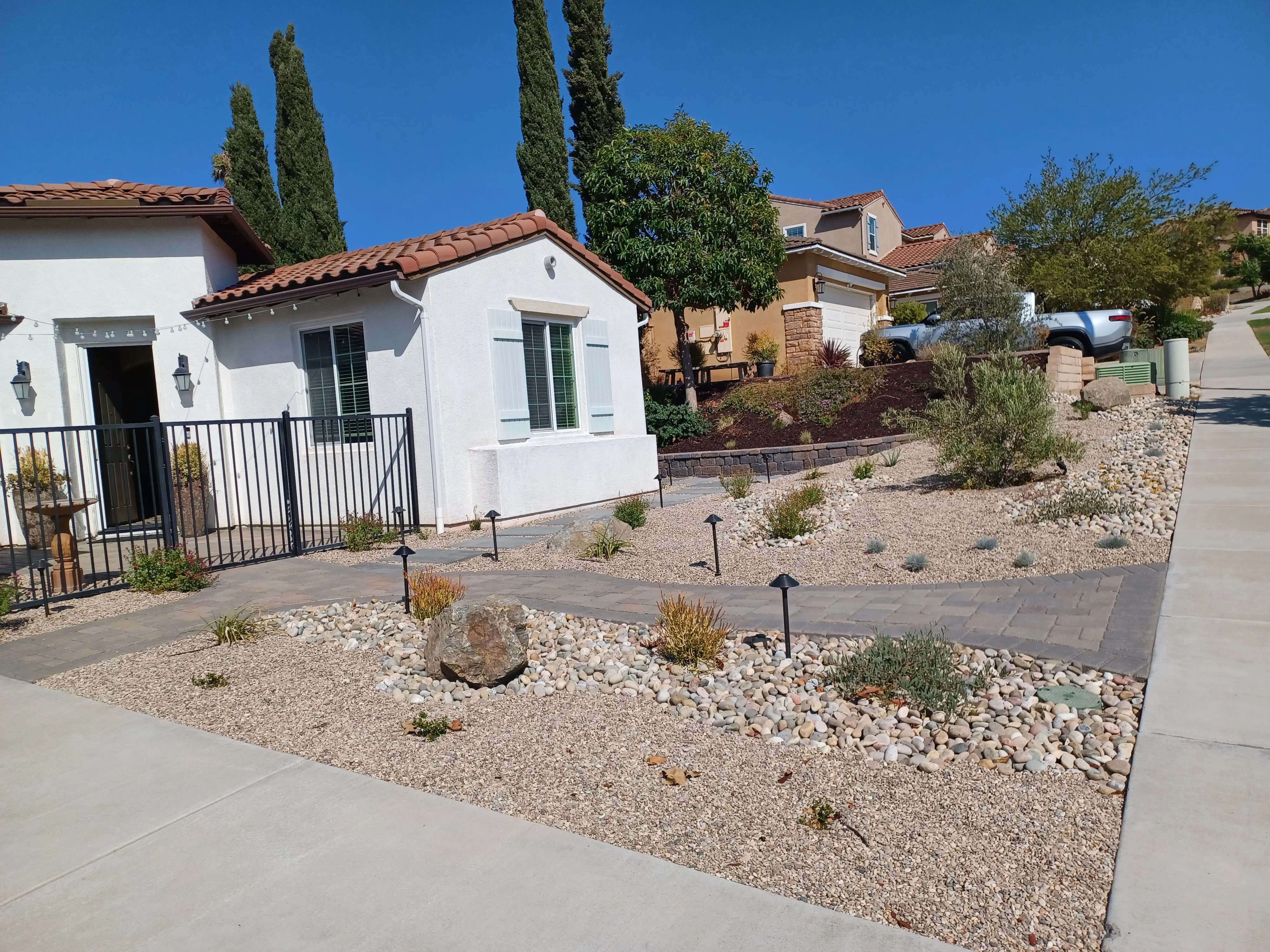 Desert xeriscape yard with gravel, river rock, concrete pavers, boulders, and landscape lighting