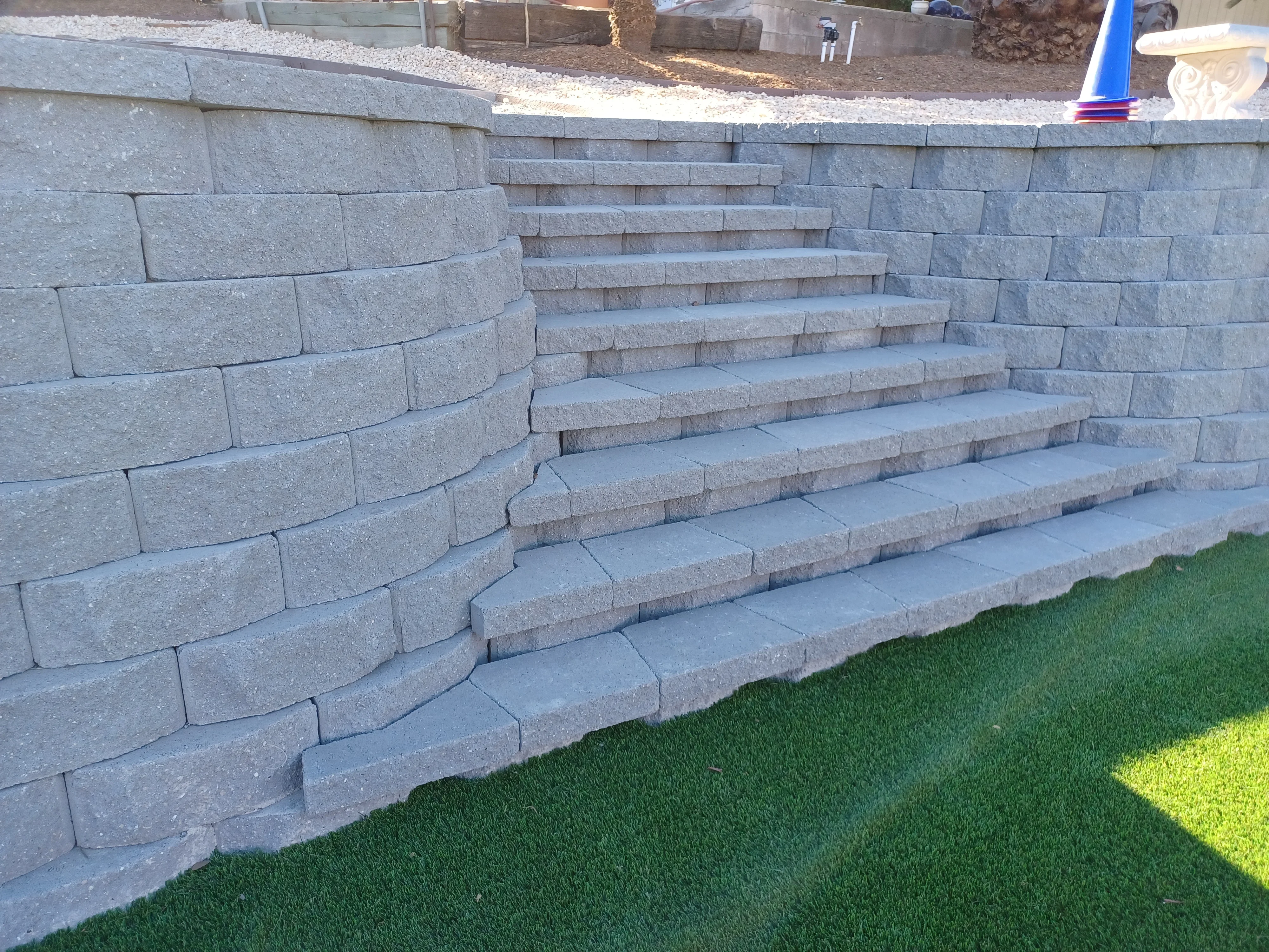 Gray concrete block retaining wall with tiered steps and curved design